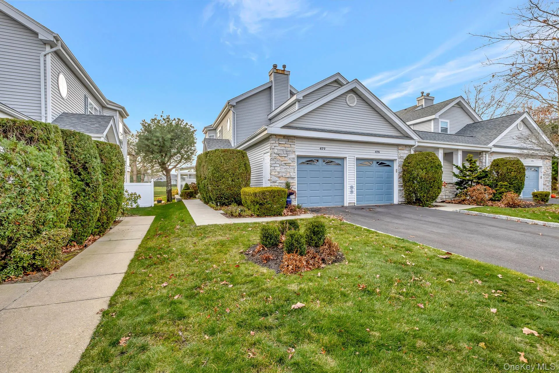 View of front facade featuring a front yard, asphalt driveway, a chimney, and a garage View of front facade featuring a front yard, asphalt driveway, a chimney, and a garage