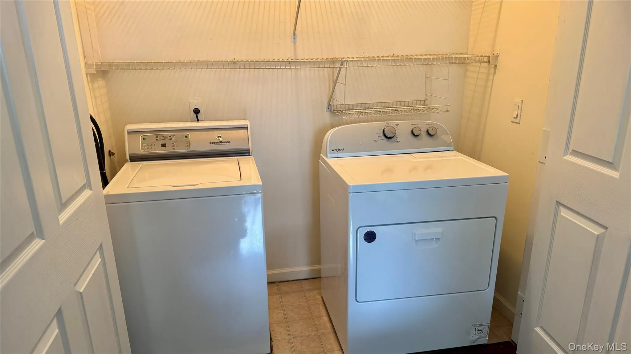 Laundry area with washing machine and clothes dryer located off hallway behind two two doors. Laundry area with washing machine and clothes dryer located off hallway behind two two doors.
