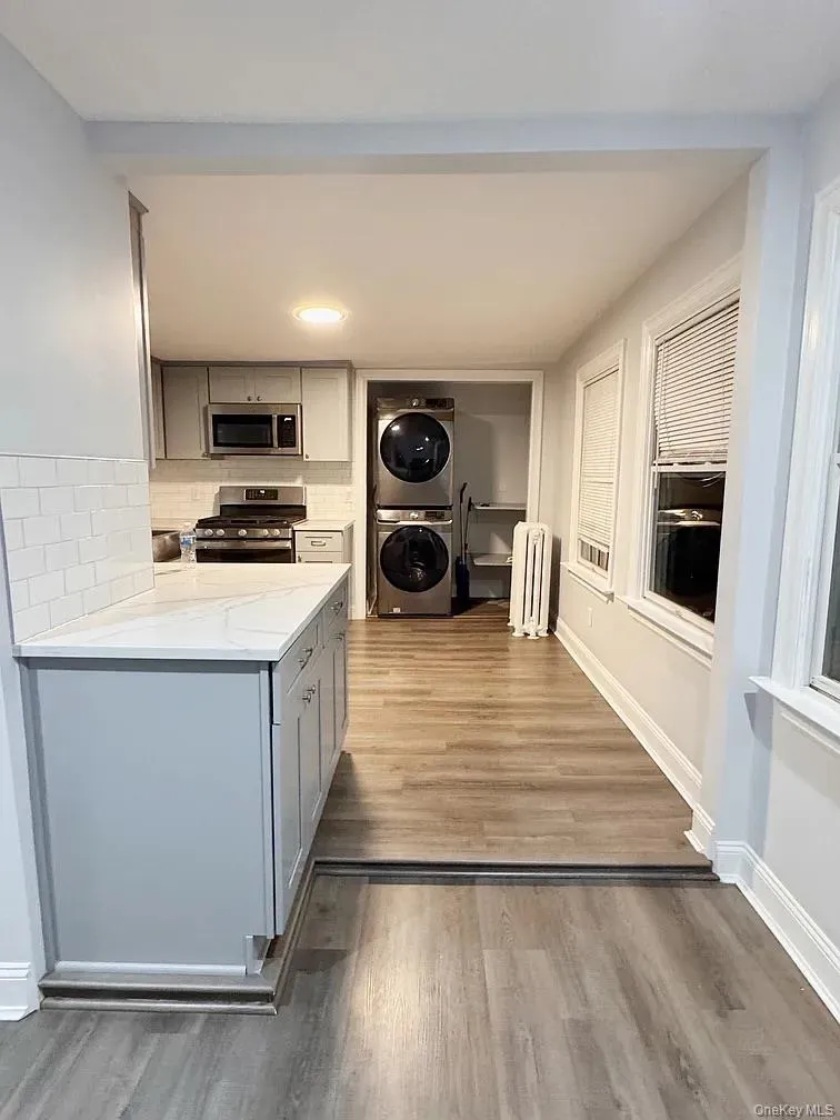 Kitchen with gray cabinets, tasteful backsplash, stainless steel appliances, stacked washer / dryer, and recessed lighting Kitchen with gray cabinets, tasteful backsplash, stainless steel appliances, stacked washer / dryer, and recessed lighting