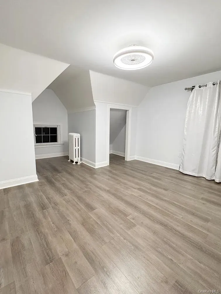Bonus room featuring lofted ceiling, radiator, and light wood-style floors Bonus room featuring lofted ceiling, radiator, and light wood-style floors