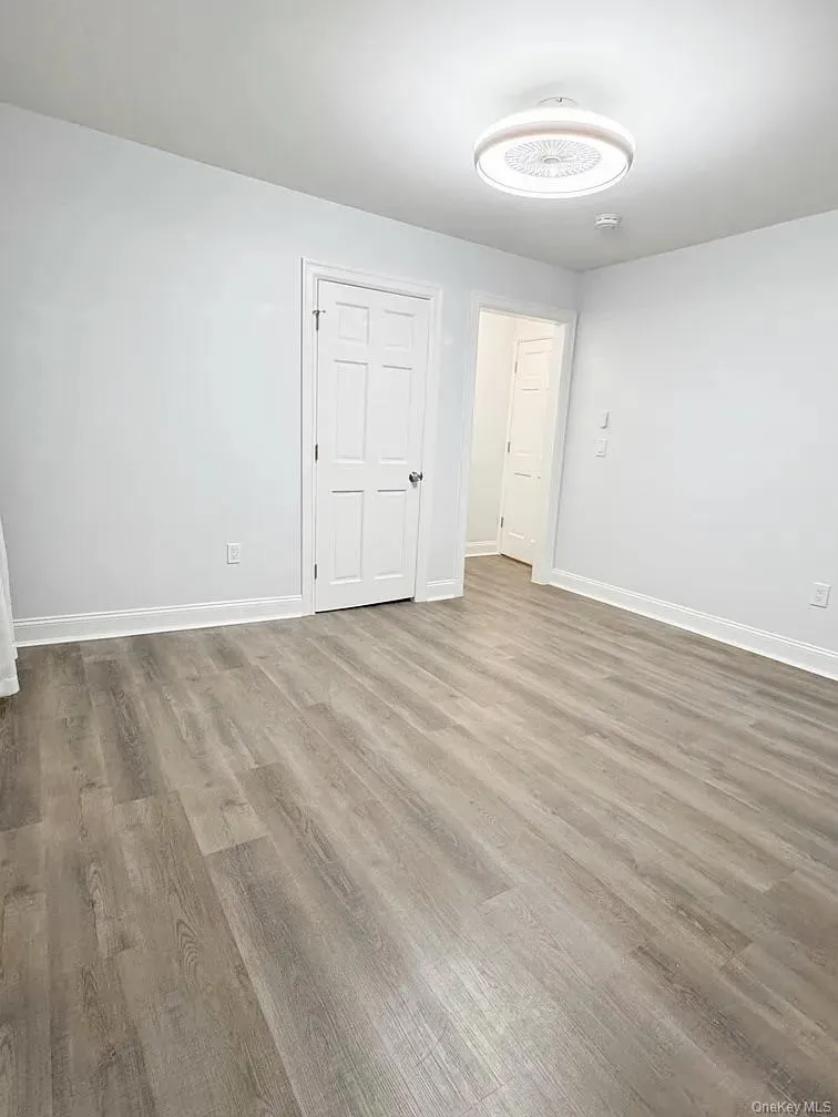 Unfurnished room with wood finished floors and baseboards Unfurnished room with wood finished floors and baseboards