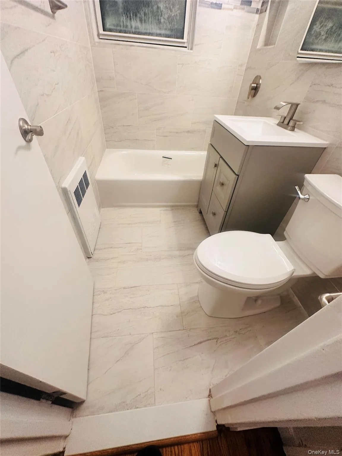Bathroom with vanity, heating unit, tile walls, and a bath Bathroom with vanity, heating unit, tile walls, and a bath