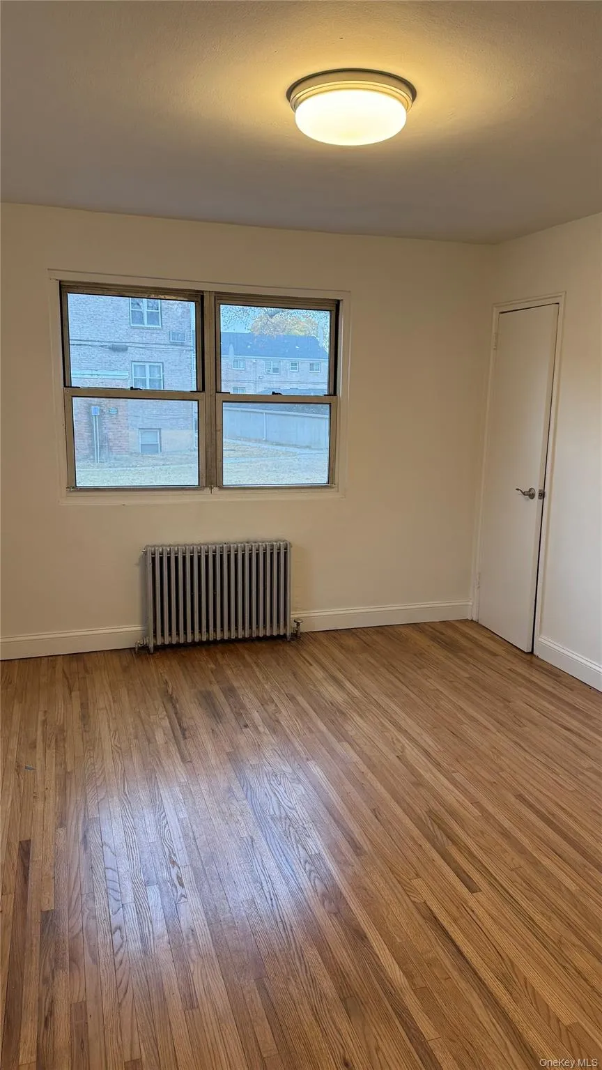 Spare room featuring radiator heating unit and light wood finished floors Spare room featuring radiator heating unit and light wood finished floors