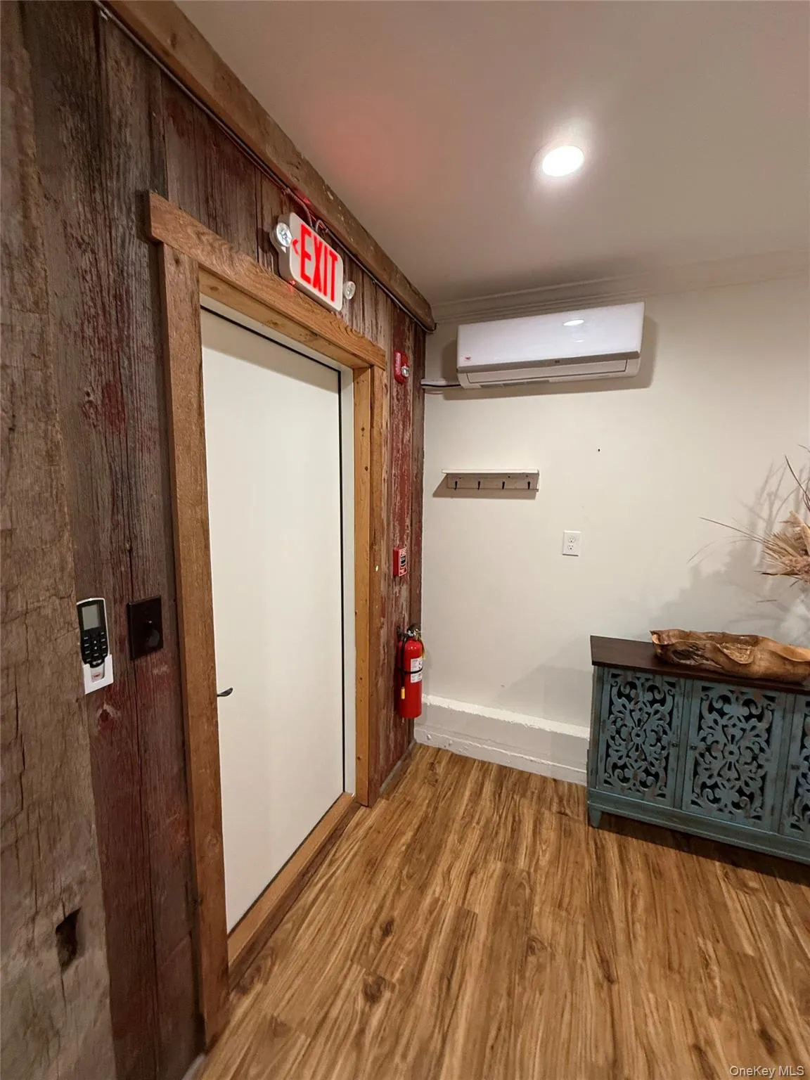 Hallway featuring wood finished floors, recessed lighting, and a wall mounted AC Hallway featuring wood finished floors, recessed lighting, and a wall mounted AC