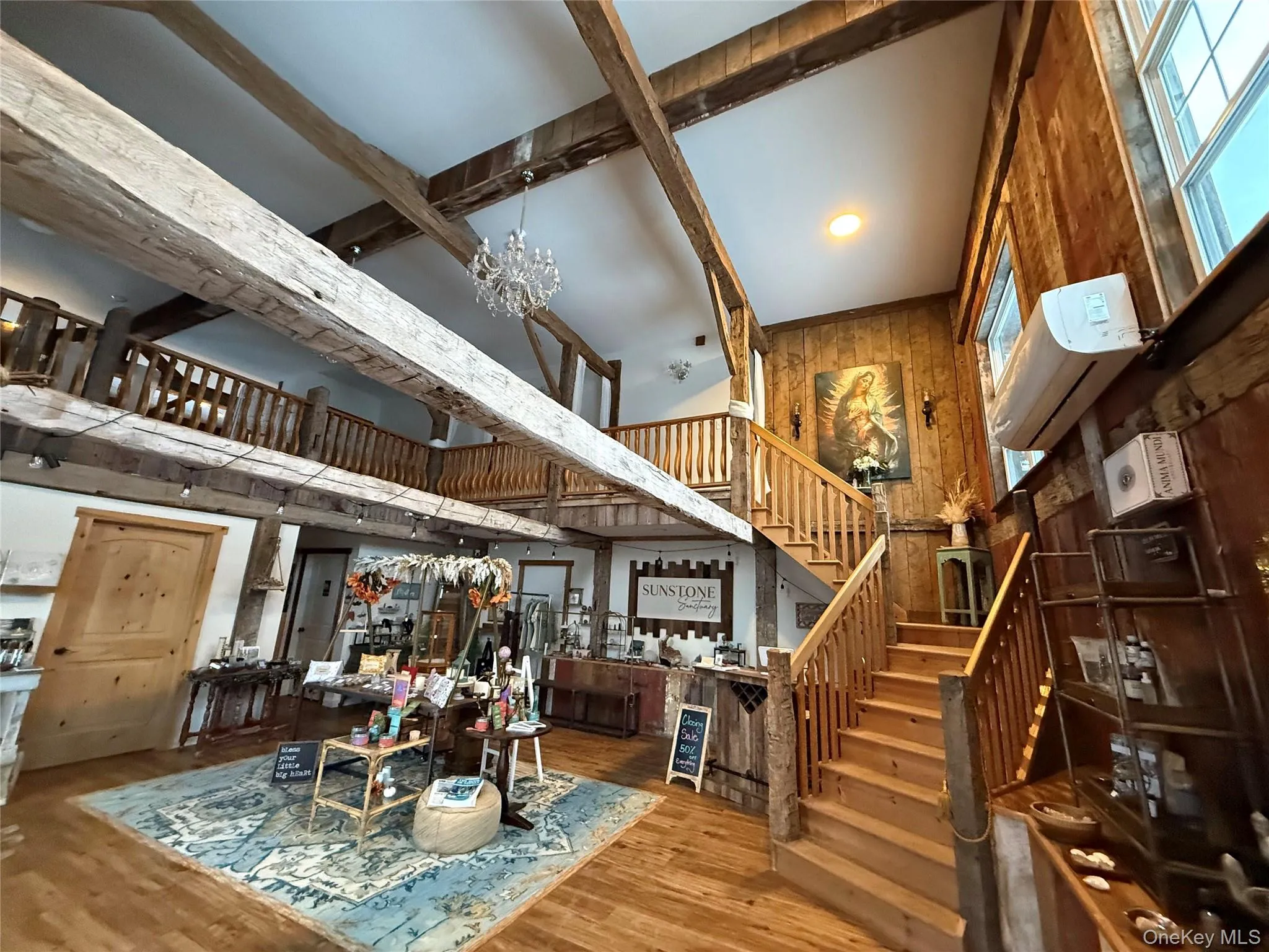Dining room with a high ceiling, wood finished floors, wooden walls, stairs, and a chandelier Dining room with a high ceiling, wood finished floors, wooden walls, stairs, and a chandelier
