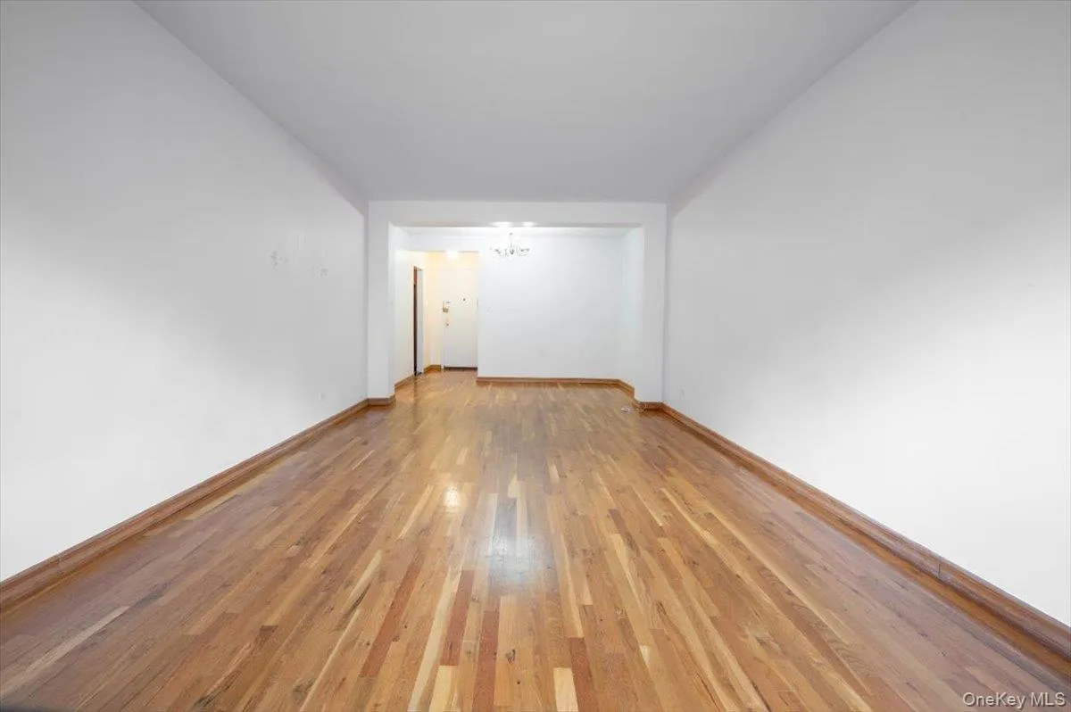Unfurnished room featuring a chandelier and light wood-type flooring Unfurnished room featuring a chandelier and light wood-type flooring