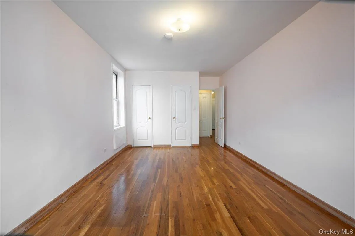Unfurnished bedroom with multiple closets and hardwood / wood-style flooring Unfurnished bedroom with multiple closets and hardwood / wood-style flooring