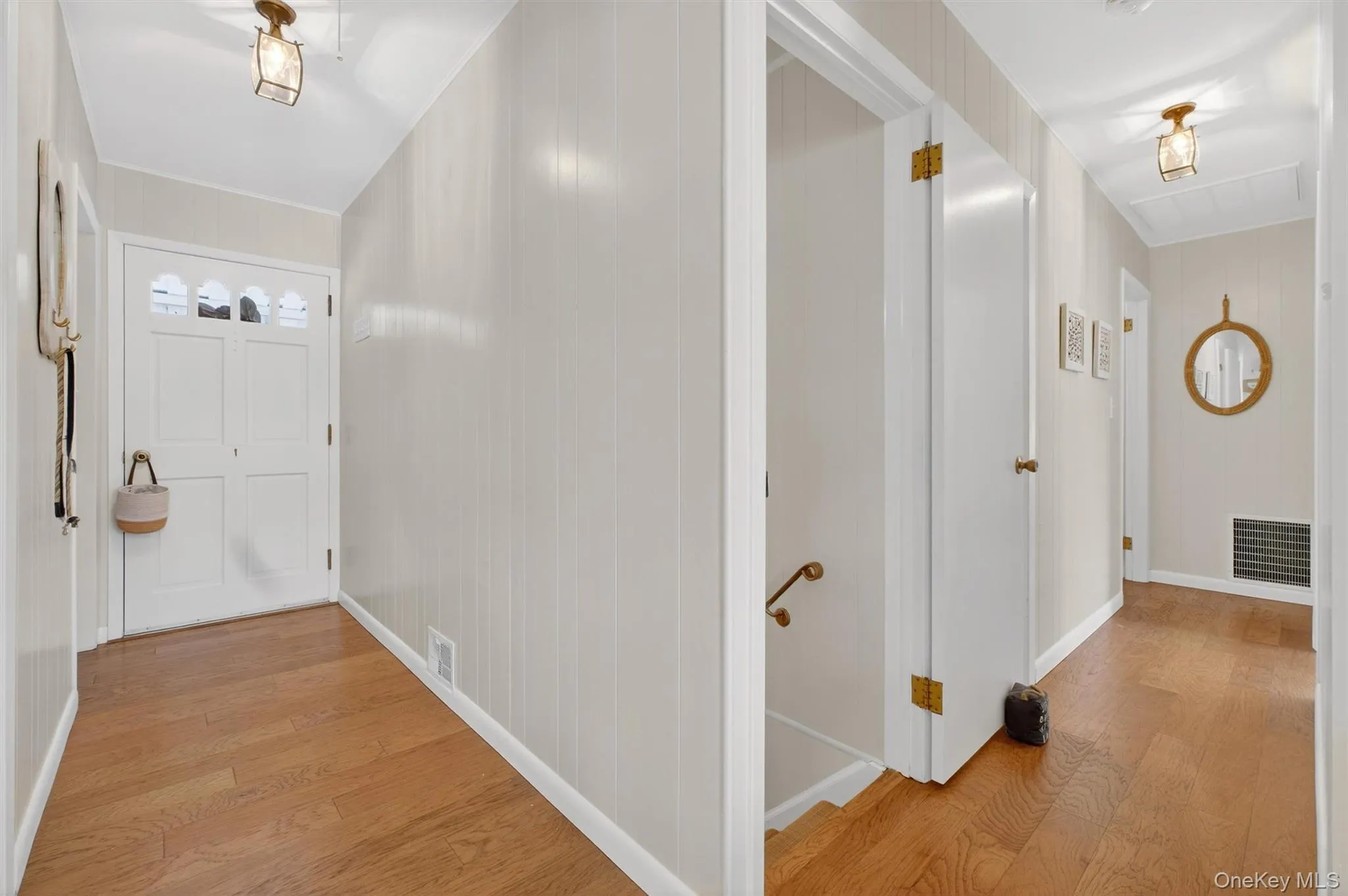 Hall featuring light wood-type flooring, an upstairs landing, and wood walls Hall featuring light wood-type flooring, an upstairs landing, and wood walls