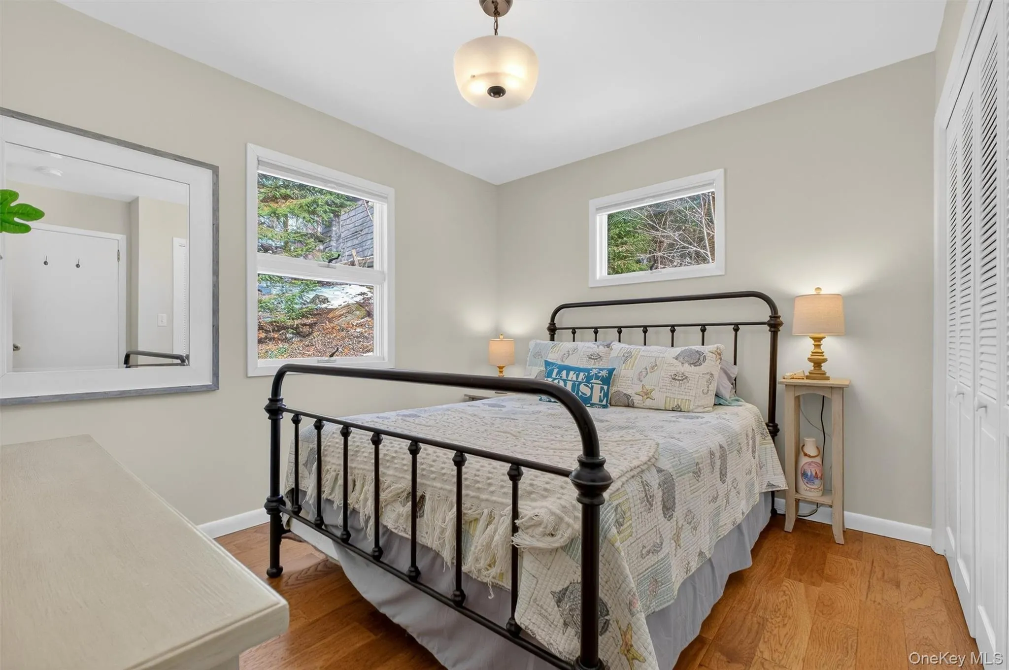 Bedroom featuring wood finished floors, multiple windows, and a closet Bedroom featuring wood finished floors, multiple windows, and a closet