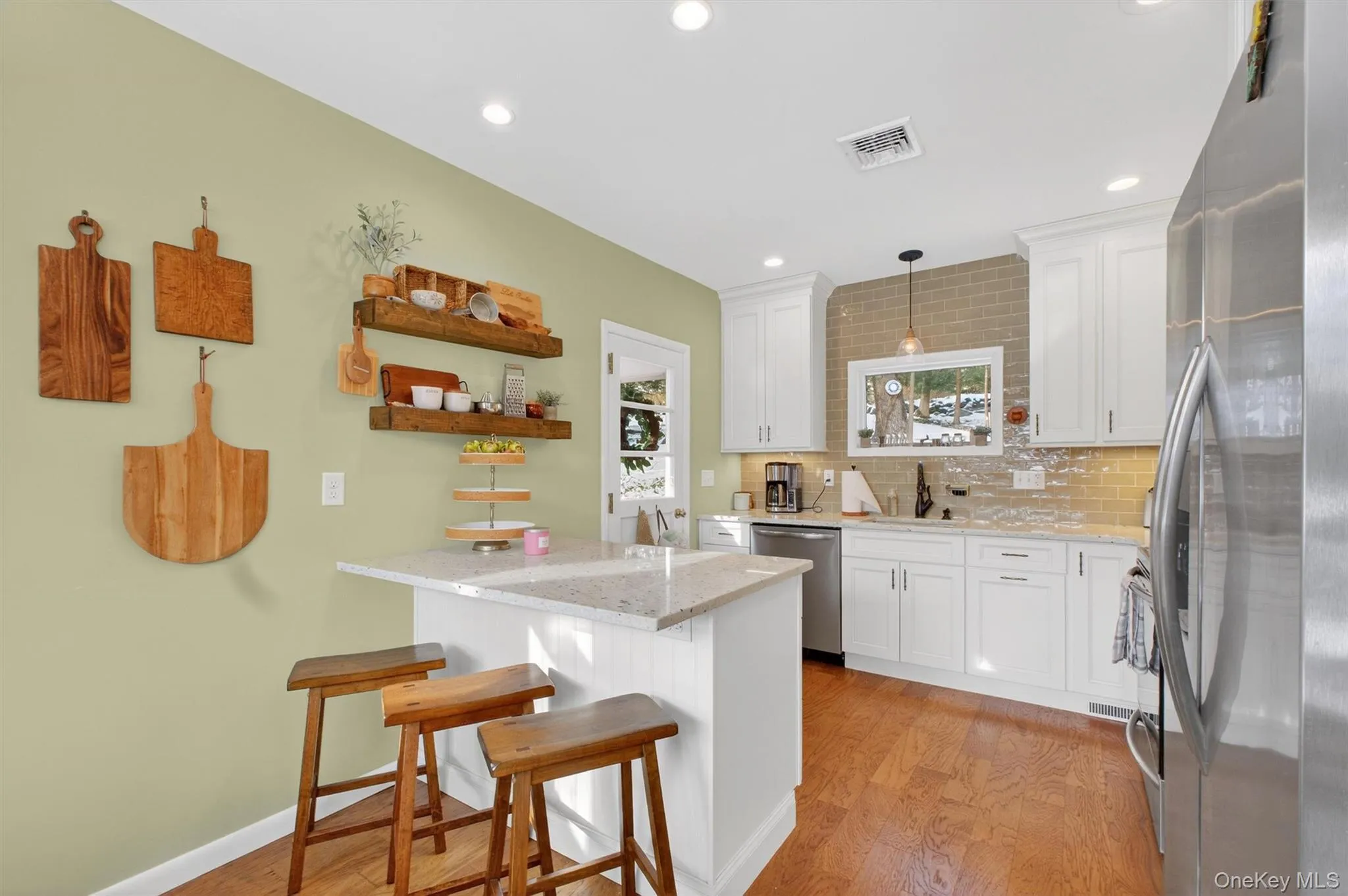 Kitchen with appliances with stainless steel finishes, white cabinetry, a breakfast bar, decorative light fixtures, and recessed lighting Kitchen with appliances with stainless steel finishes, white cabinetry, a breakfast bar, decorative light fixtures, and recessed lighting
