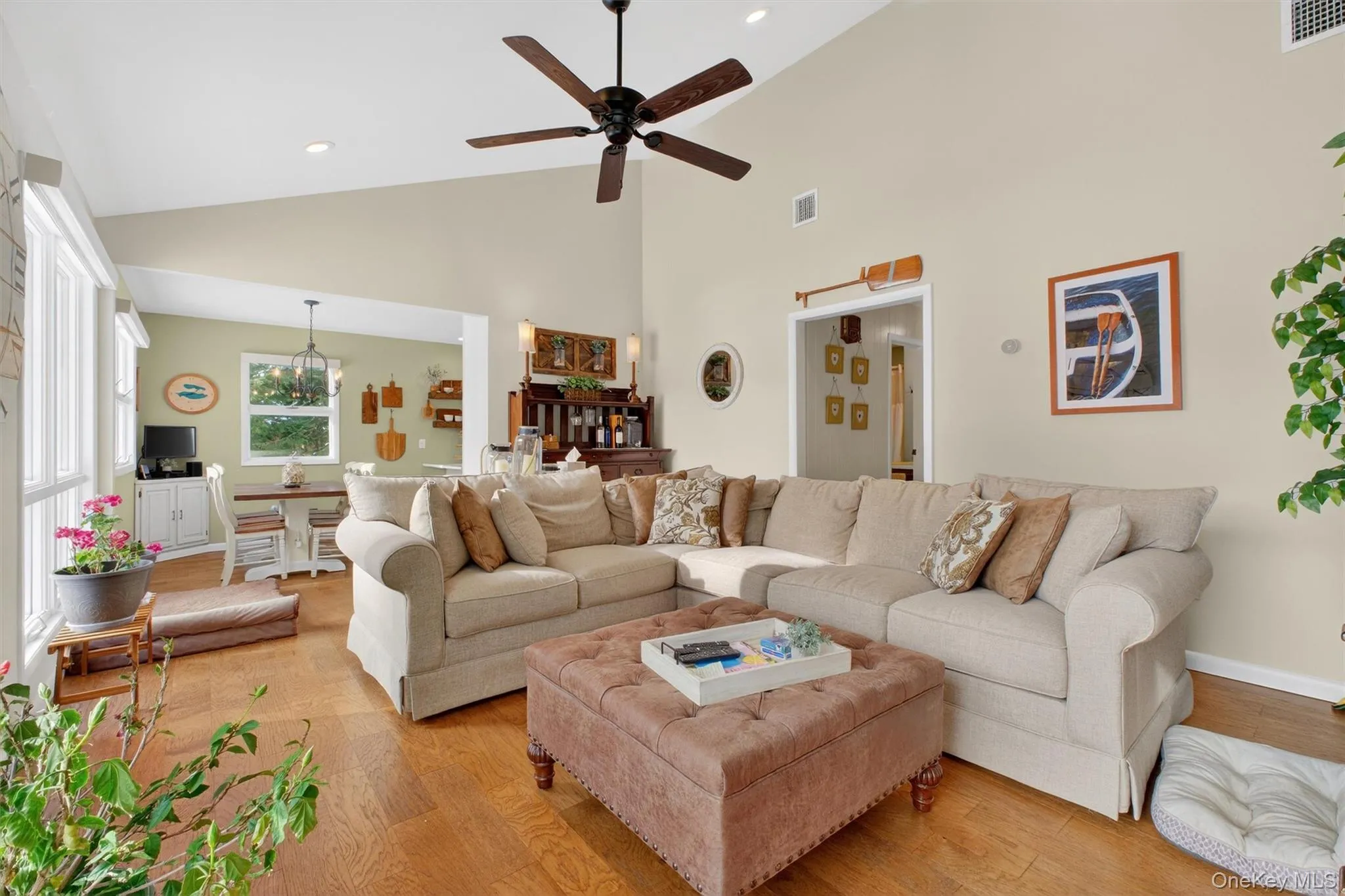 Living area featuring high vaulted ceiling, a ceiling fan, wood finished floors, and recessed lighting Living area featuring high vaulted ceiling, a ceiling fan, wood finished floors, and recessed lighting