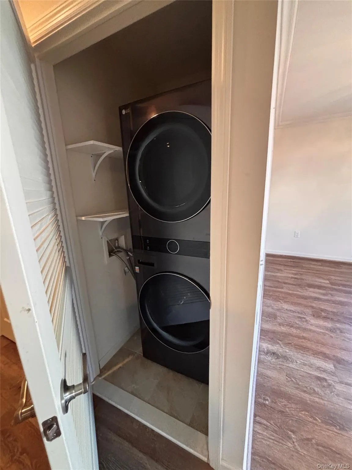 Laundry area featuring wood finished floors and stacked washer / drying machine Laundry area featuring wood finished floors and stacked washer / drying machine