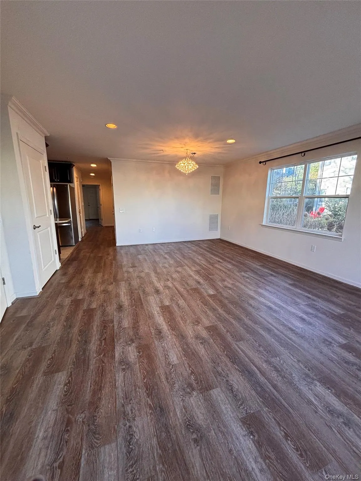 Unfurnished living room with dark wood-style flooring, recessed lighting, and a chandelier Unfurnished living room with dark wood-style flooring, recessed lighting, and a chandelier