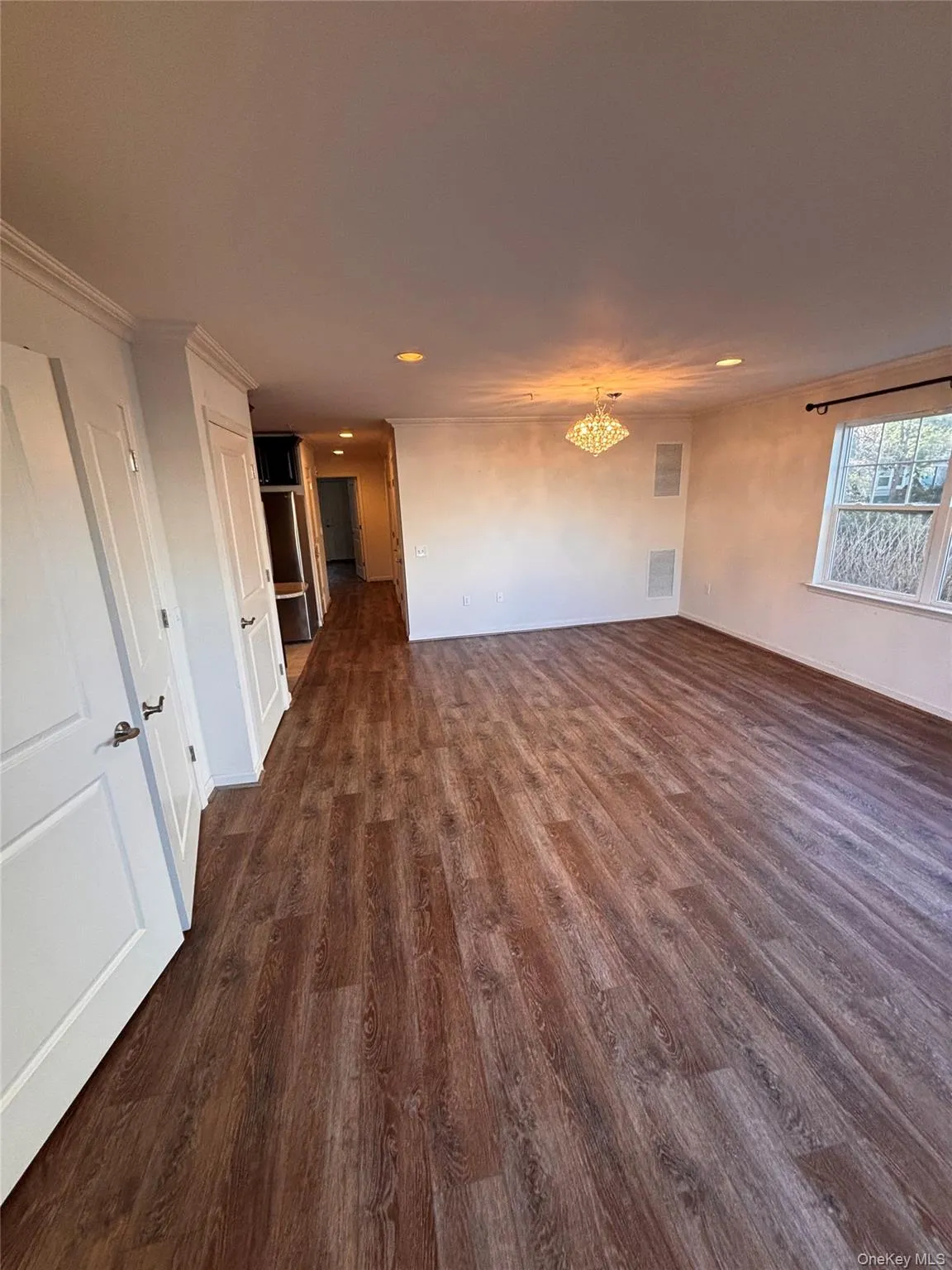 Empty room featuring dark wood-type flooring and a chandelier Empty room featuring dark wood-type flooring and a chandelier