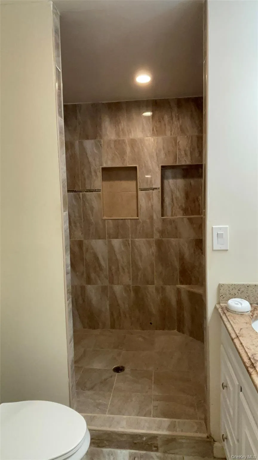 Full bathroom with vanity, tiled shower, and recessed lighting Full bathroom with vanity, tiled shower, and recessed lighting