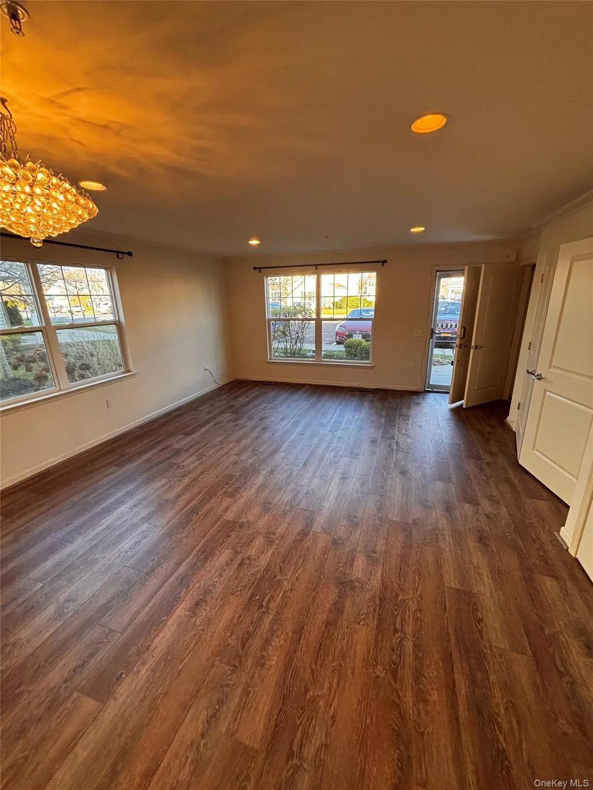 Unfurnished room featuring dark wood-style flooring, plenty of natural light, recessed lighting, and a chandelier Unfurnished room featuring dark wood-style flooring, plenty of natural light, recessed lighting, and a chandelier