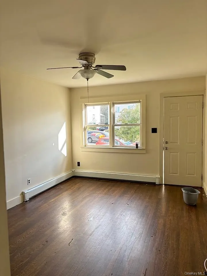 Entryway featuring dark wood-style flooring, a baseboard heating unit, and a ceiling fan Entryway featuring dark wood-style flooring, a baseboard heating unit, and a ceiling fan