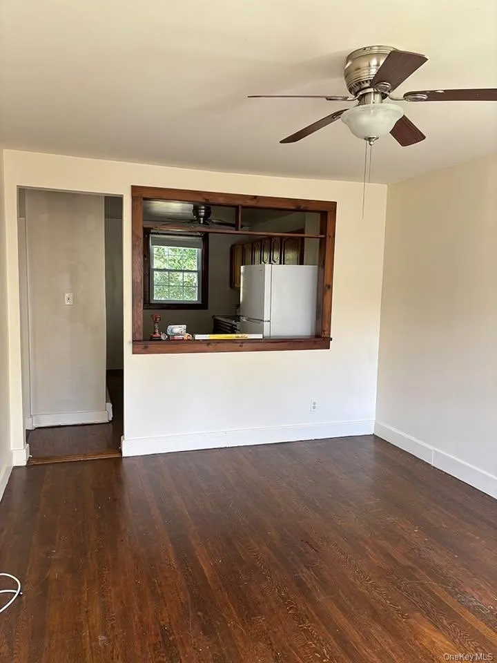 Unfurnished living room with ceiling fan and dark wood-style floors Unfurnished living room with ceiling fan and dark wood-style floors