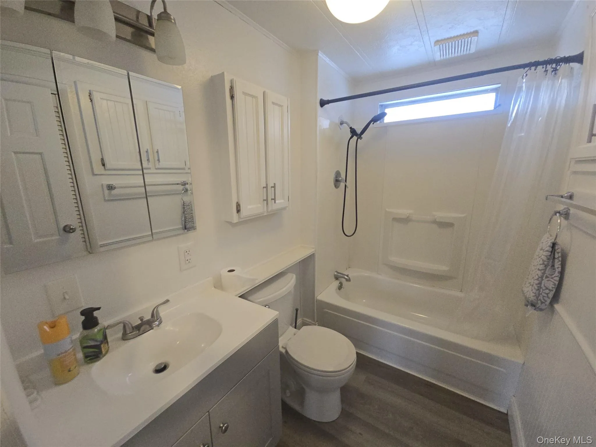 Bathroom with shower / tub combo, dark wood-type flooring, vanity, and ornamental molding Bathroom with shower / tub combo, dark wood-type flooring, vanity, and ornamental molding