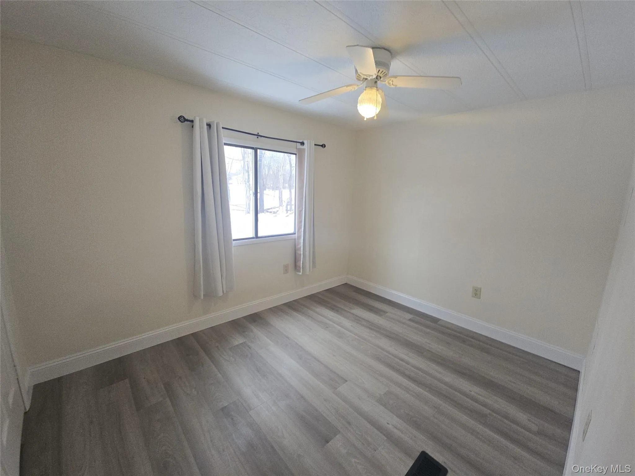 Empty room featuring wood finished floors and a ceiling fan Empty room featuring wood finished floors and a ceiling fan