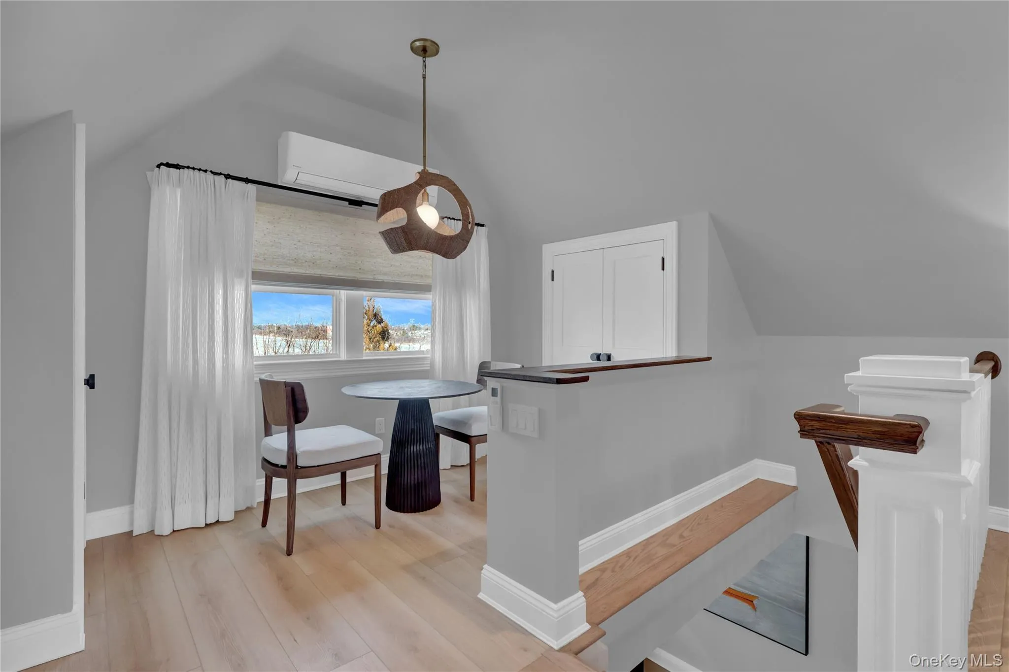 Dining space featuring light wood finished floors, lofted ceiling, and a wall mounted AC Dining space featuring light wood finished floors, lofted ceiling, and a wall mounted AC