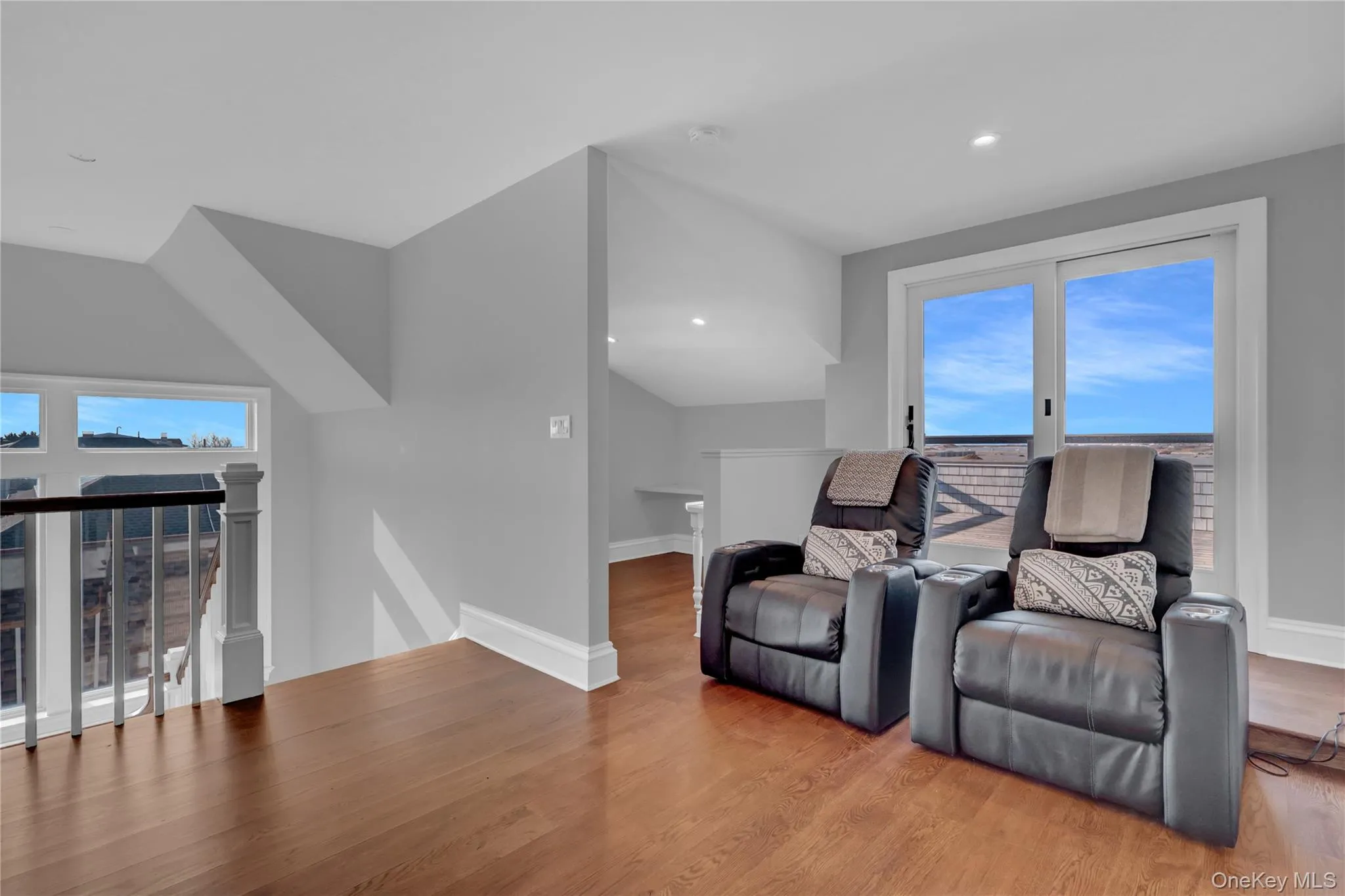 Living area featuring an upstairs landing, plenty of natural light, wood finished floors, and recessed lighting Living area featuring an upstairs landing, plenty of natural light, wood finished floors, and recessed lighting