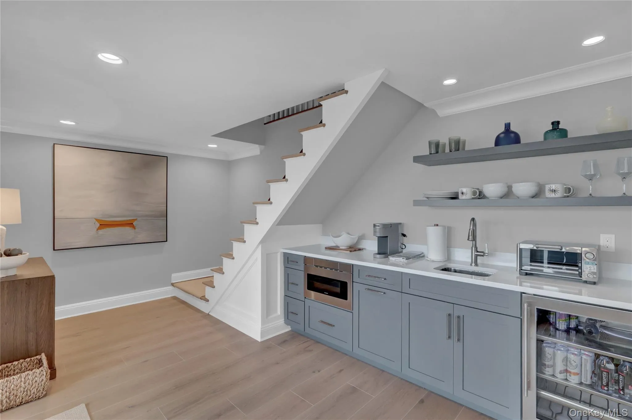 Bar area with open shelves, light wood finished floors, light stone countertops, stairway, and recessed lighting Bar area with open shelves, light wood finished floors, light stone countertops, stairway, and recessed lighting