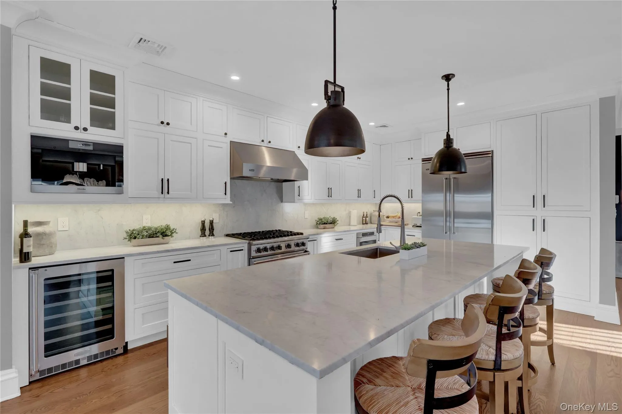 Kitchen featuring white cabinetry, beverage cooler, premium appliances, a breakfast bar area, and recessed lighting Kitchen featuring white cabinetry, beverage cooler, premium appliances, a breakfast bar area, and recessed lighting