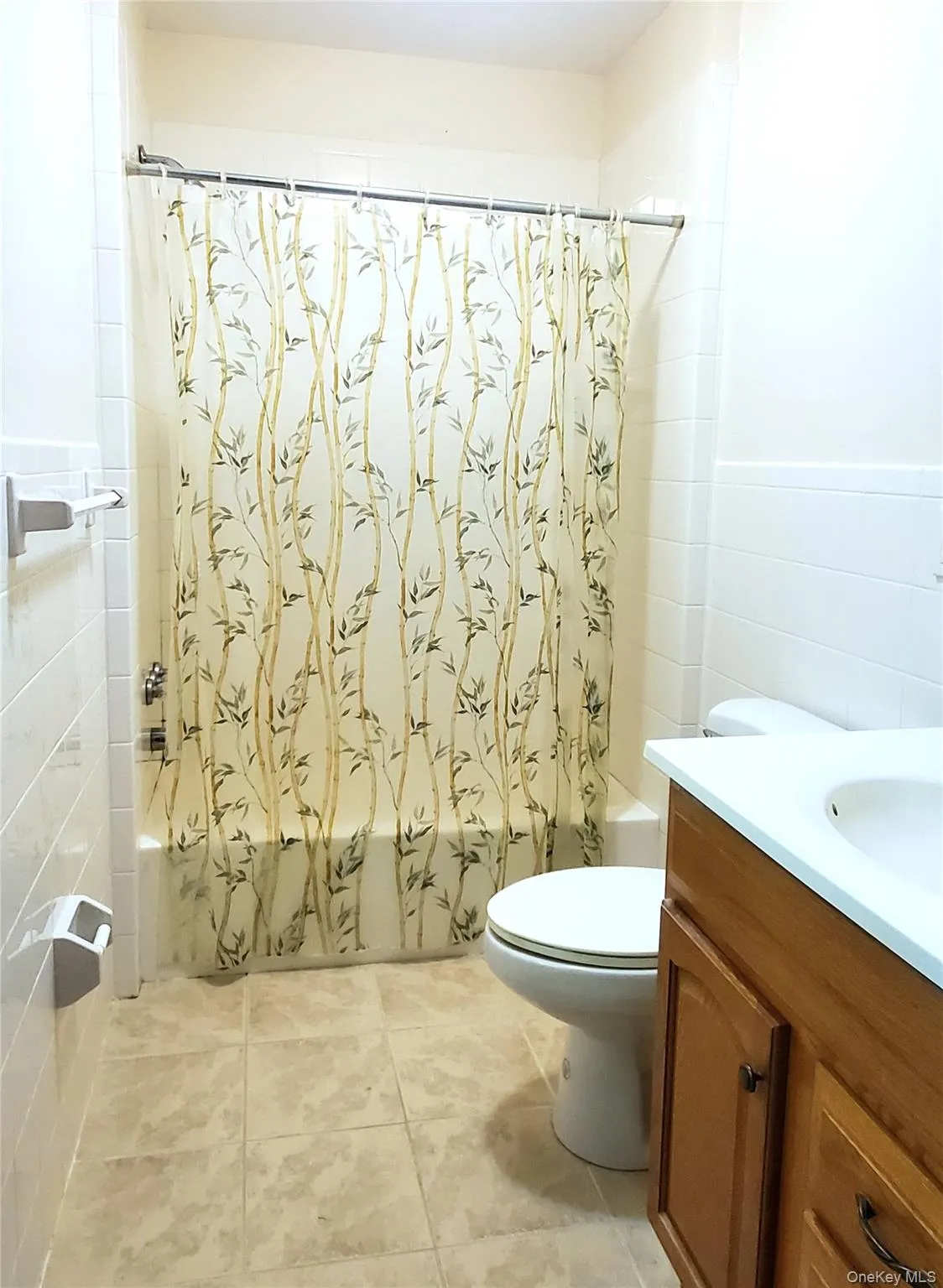 Full bathroom with tile walls, shower / bath combo with vanity, and light tile patterned floors Full bathroom with tile walls, shower / bath combo with vanity, and light tile patterned floors