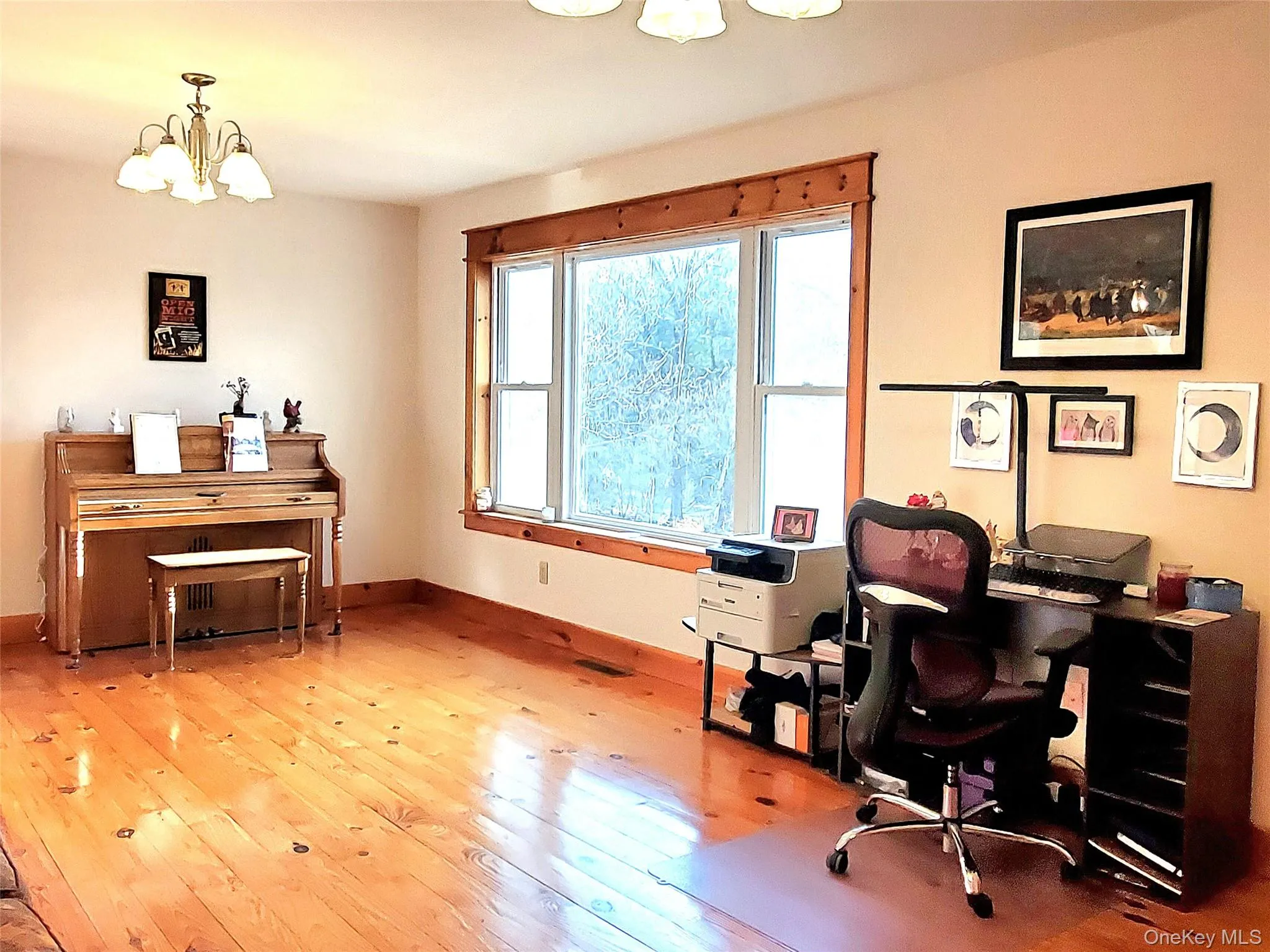 Living room with large window looking out to front yard, wide plank hardwood floors and beautiful wood detail Living room with large window looking out to front yard, wide plank hardwood floors and beautiful wood detail
