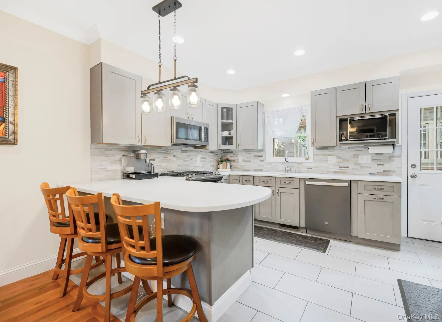 Kitchen featuring gray cabinets, a breakfast bar, appliances with stainless steel finishes, a peninsula, and recessed lighting Kitchen featuring gray cabinets, a breakfast bar, appliances with stainless steel finishes, a peninsula, and recessed lighting