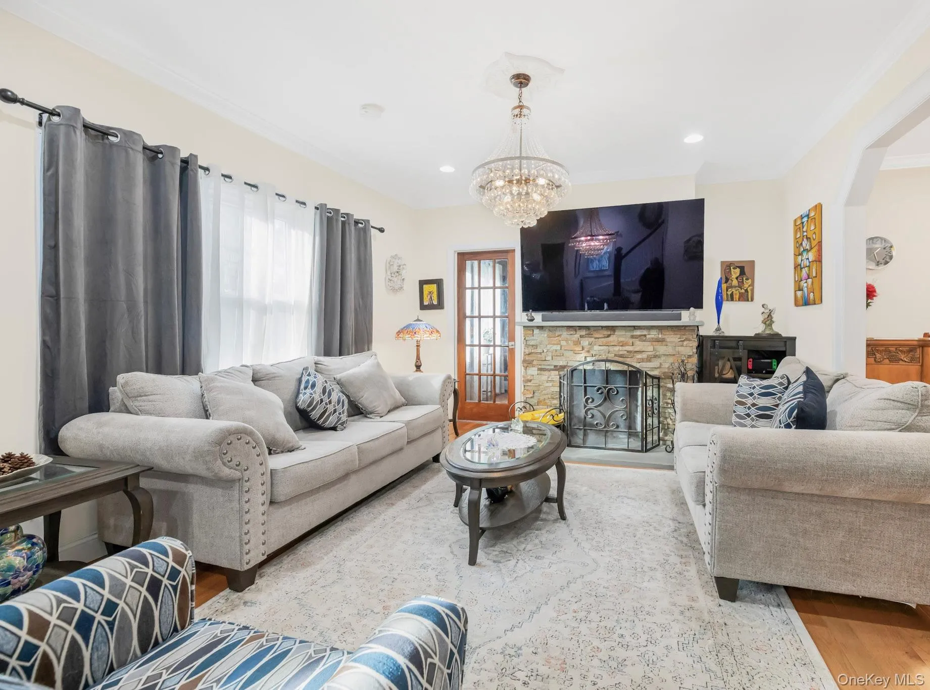 Living room with wood finished floors, a fireplace, crown molding, a chandelier, and recessed lighting Living room with wood finished floors, a fireplace, crown molding, a chandelier, and recessed lighting