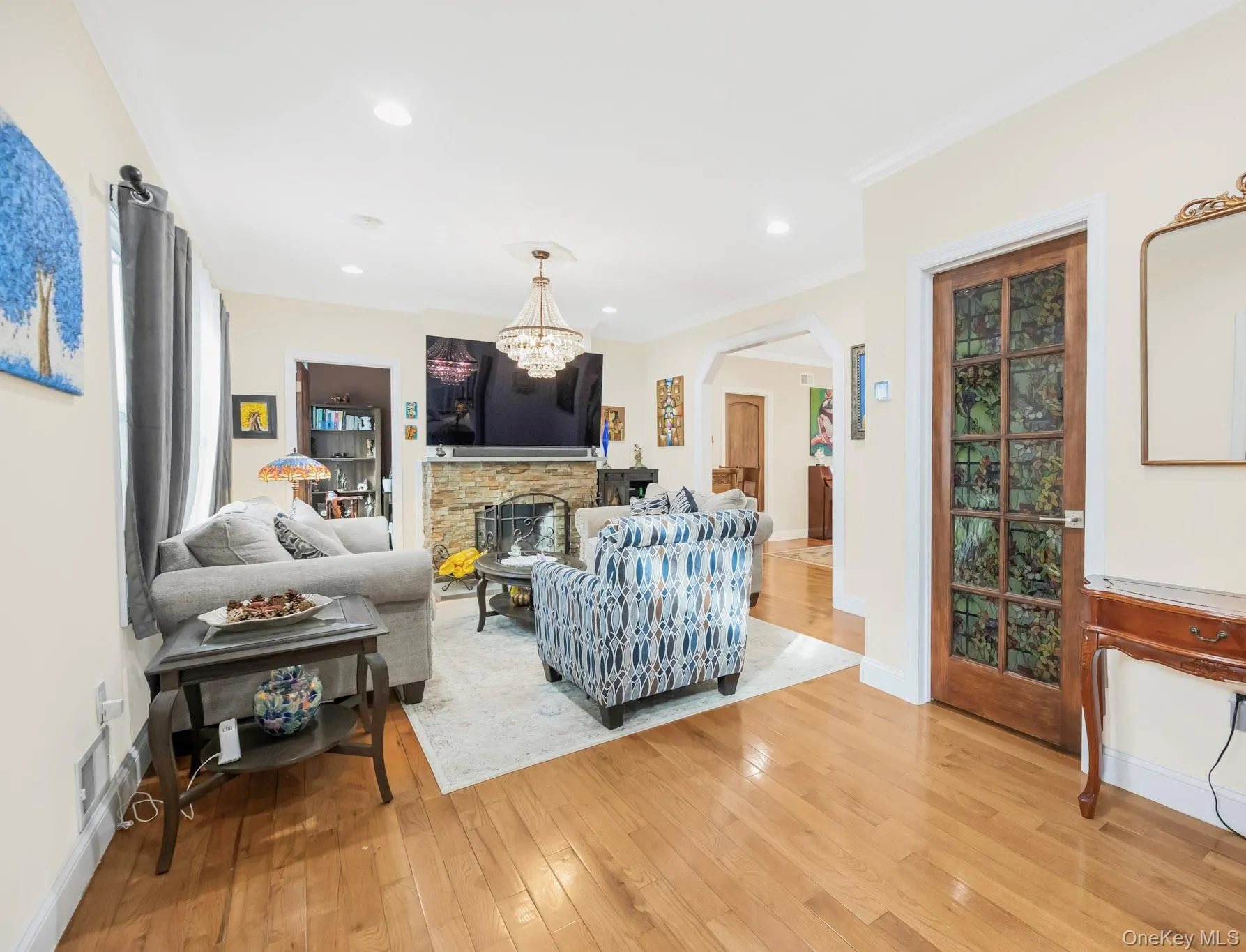Living area with a fireplace, light wood-style flooring, arched walkways, recessed lighting, and ornamental molding Living area with a fireplace, light wood-style flooring, arched walkways, recessed lighting, and ornamental molding