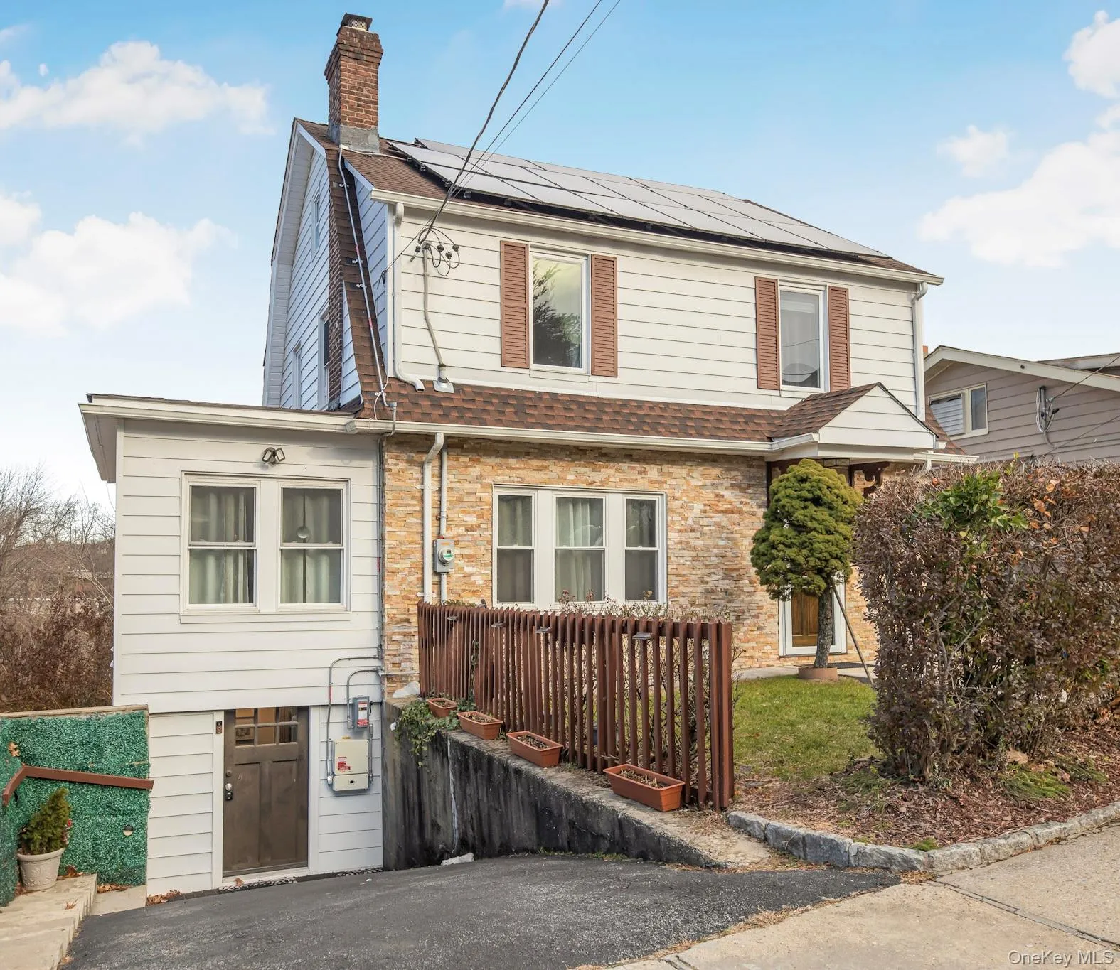 View of front of house with a chimney, roof mounted solar panels, a shingled roof, and brick siding View of front of house with a chimney, roof mounted solar panels, a shingled roof, and brick siding