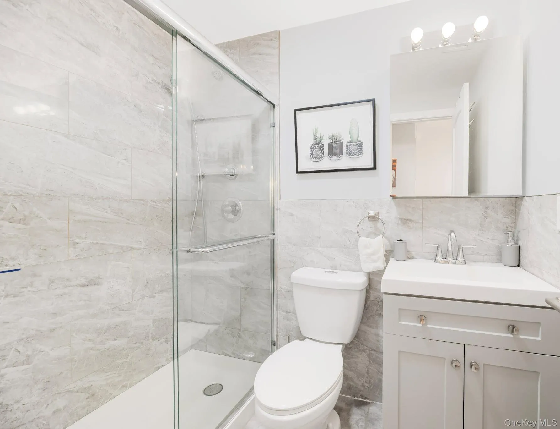 Bathroom with vanity, a shower stall, and tile walls Bathroom with vanity, a shower stall, and tile walls