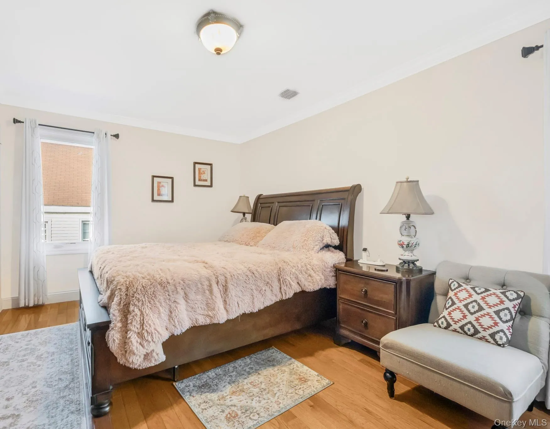 Bedroom featuring light wood finished floors and crown molding Bedroom featuring light wood finished floors and crown molding
