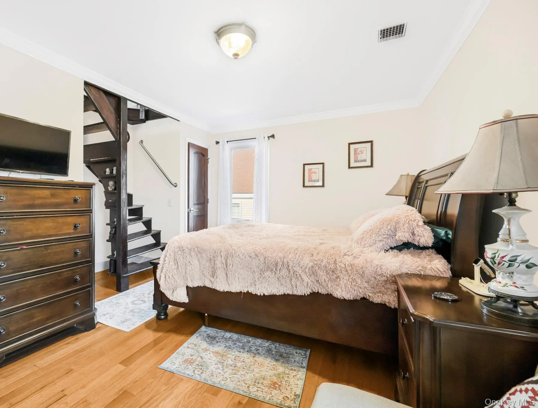Bedroom featuring ornamental molding and light wood finished floors Bedroom featuring ornamental molding and light wood finished floors