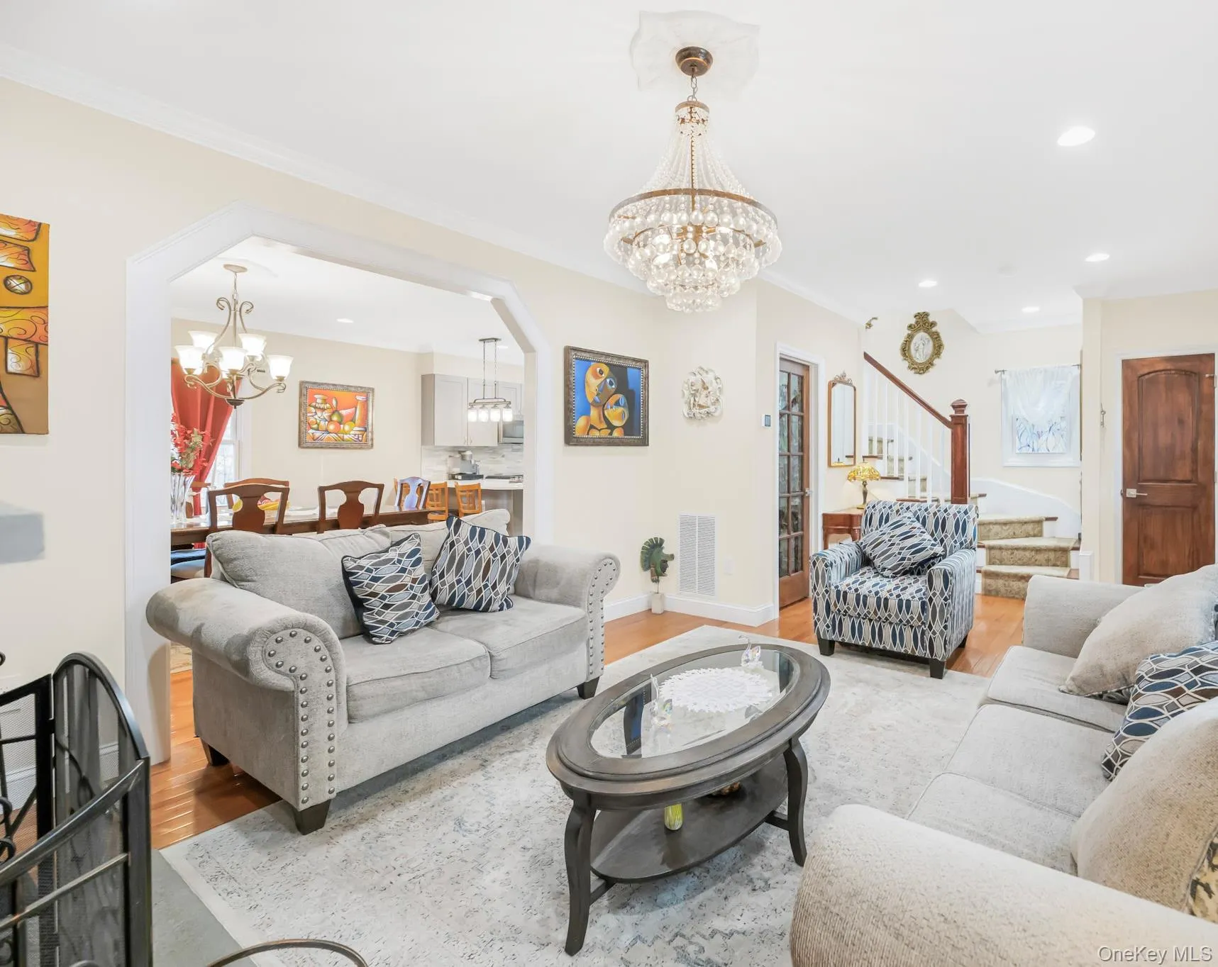 Living room featuring a chandelier, stairway, wood finished floors, recessed lighting, and ornamental molding Living room featuring a chandelier, stairway, wood finished floors, recessed lighting, and ornamental molding