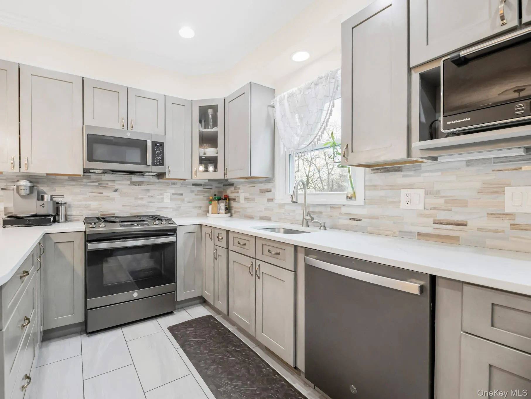 Kitchen featuring gray cabinets, appliances with stainless steel finishes, light tile patterned flooring, and recessed lighting Kitchen featuring gray cabinets, appliances with stainless steel finishes, light tile patterned flooring, and recessed lighting