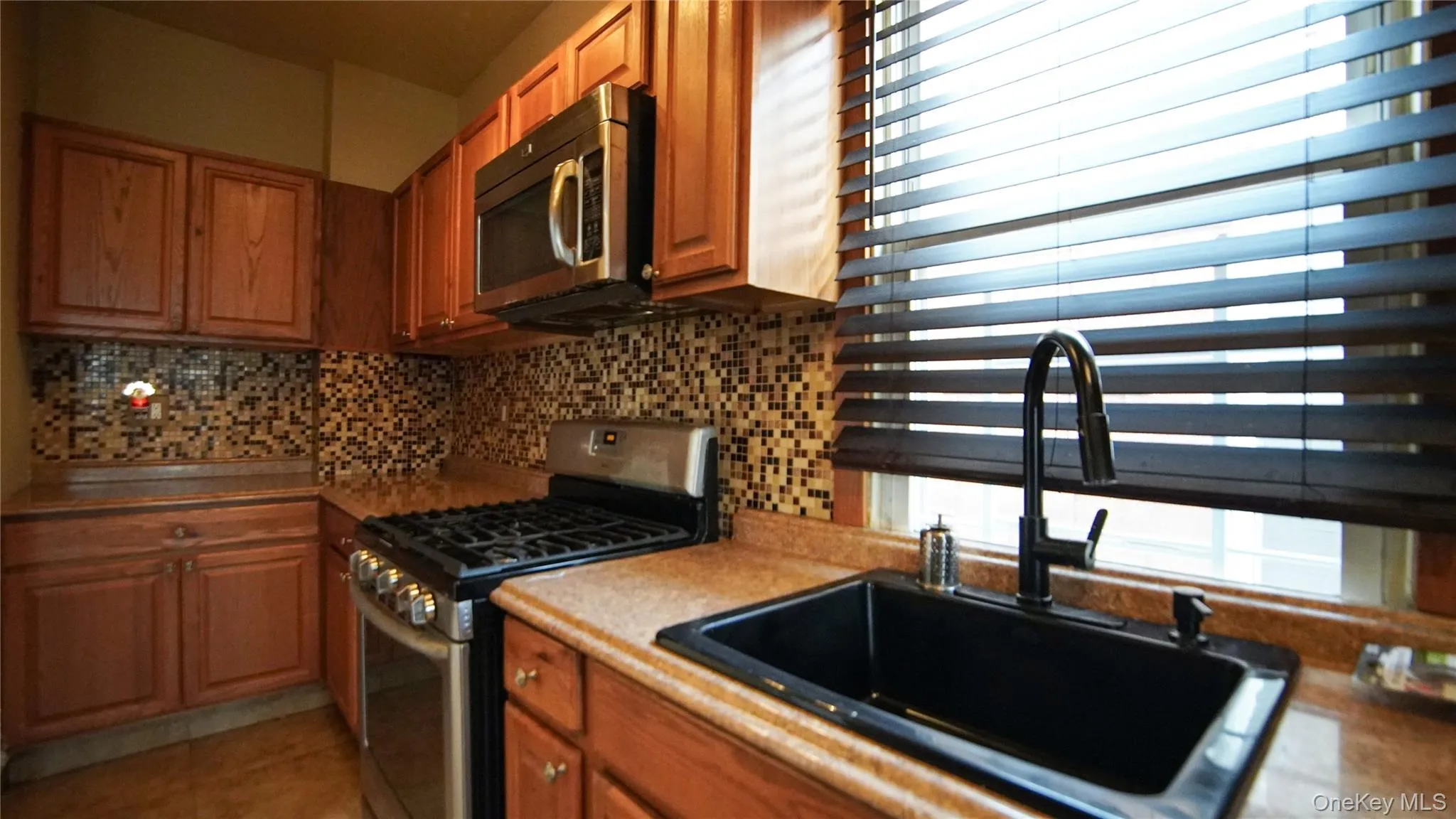 Kitchen featuring stainless steel appliances, wood finish cabinets, and tasteful backsplash Kitchen featuring stainless steel appliances, wood finish cabinets, and tasteful backsplash
