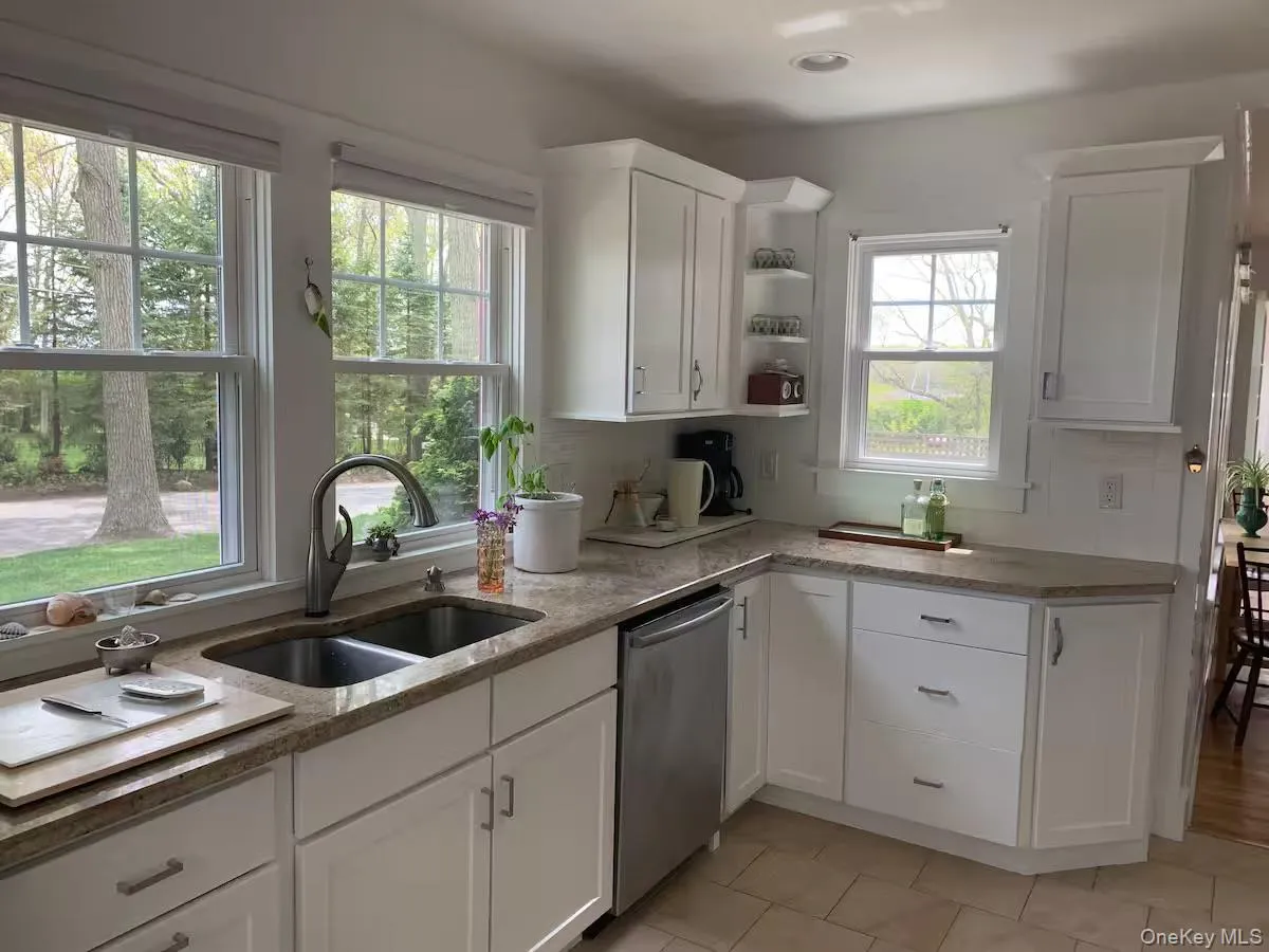 Kitchen featuring white cabinetry, open shelves, dishwasher, light stone countertops, and light tile patterned flooring Kitchen featuring white cabinetry, open shelves, dishwasher, light stone countertops, and light tile patterned flooring