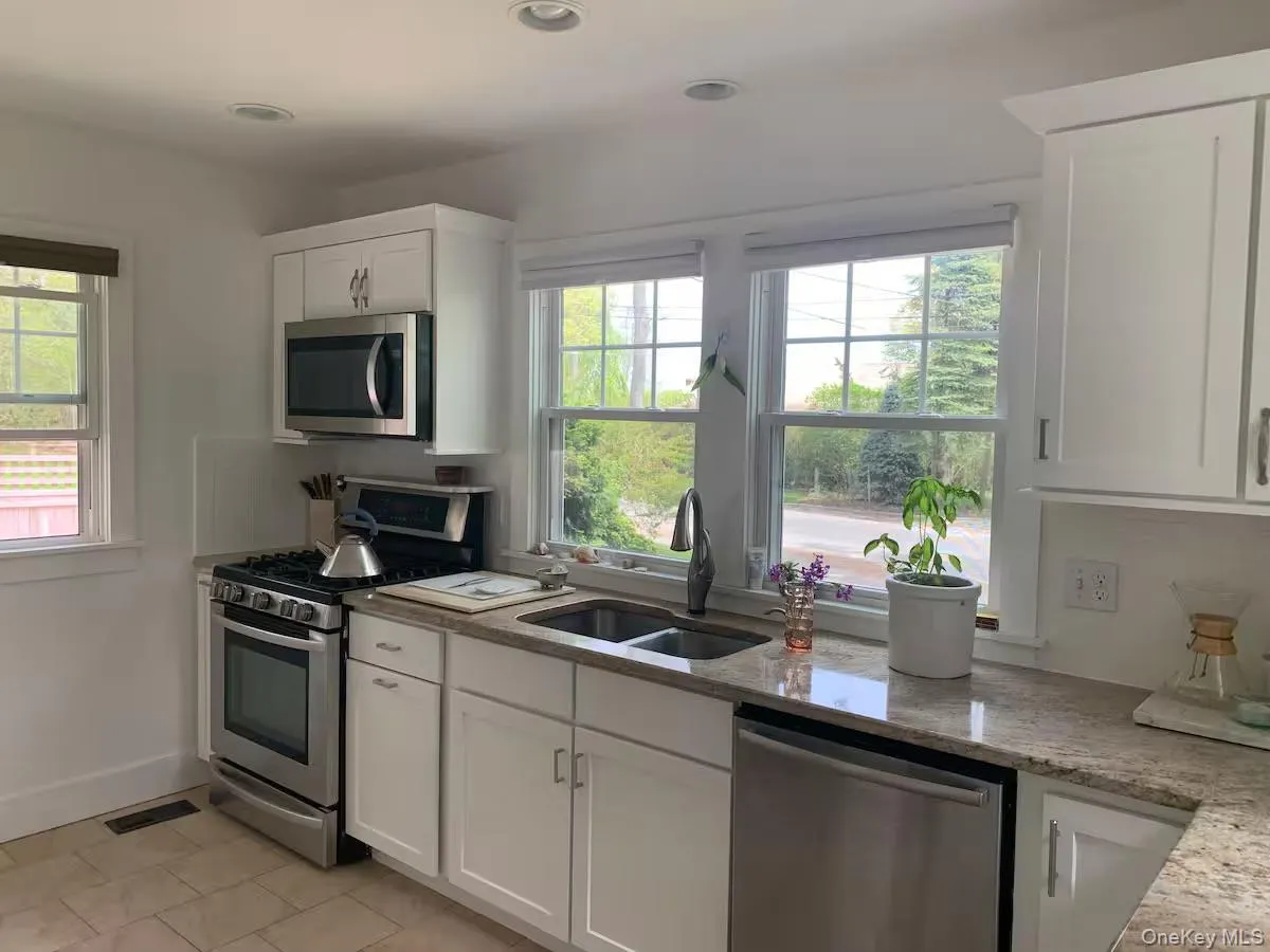 Kitchen featuring appliances with stainless steel finishes, white cabinets, light stone countertops, plenty of natural light, and recessed lighting Kitchen featuring appliances with stainless steel finishes, white cabinets, light stone countertops, plenty of natural light, and recessed lighting