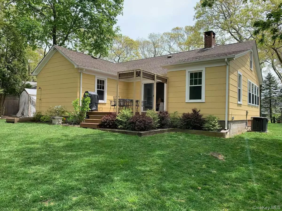 Rear view of house featuring a chimney, a lawn, a deck, a shingled roof, and a storage shed Rear view of house featuring a chimney, a lawn, a deck, a shingled roof, and a storage shed