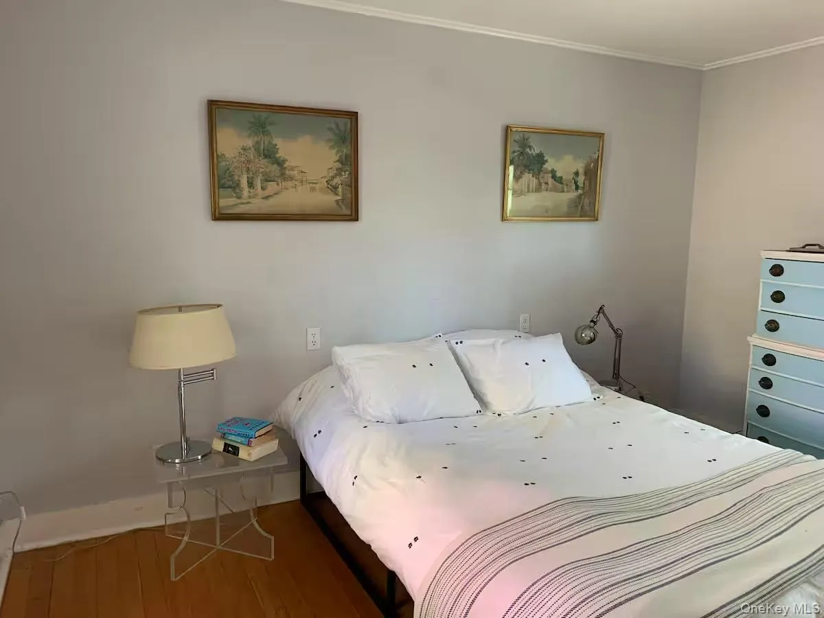 Bedroom featuring wood finished floors and crown molding Bedroom featuring wood finished floors and crown molding