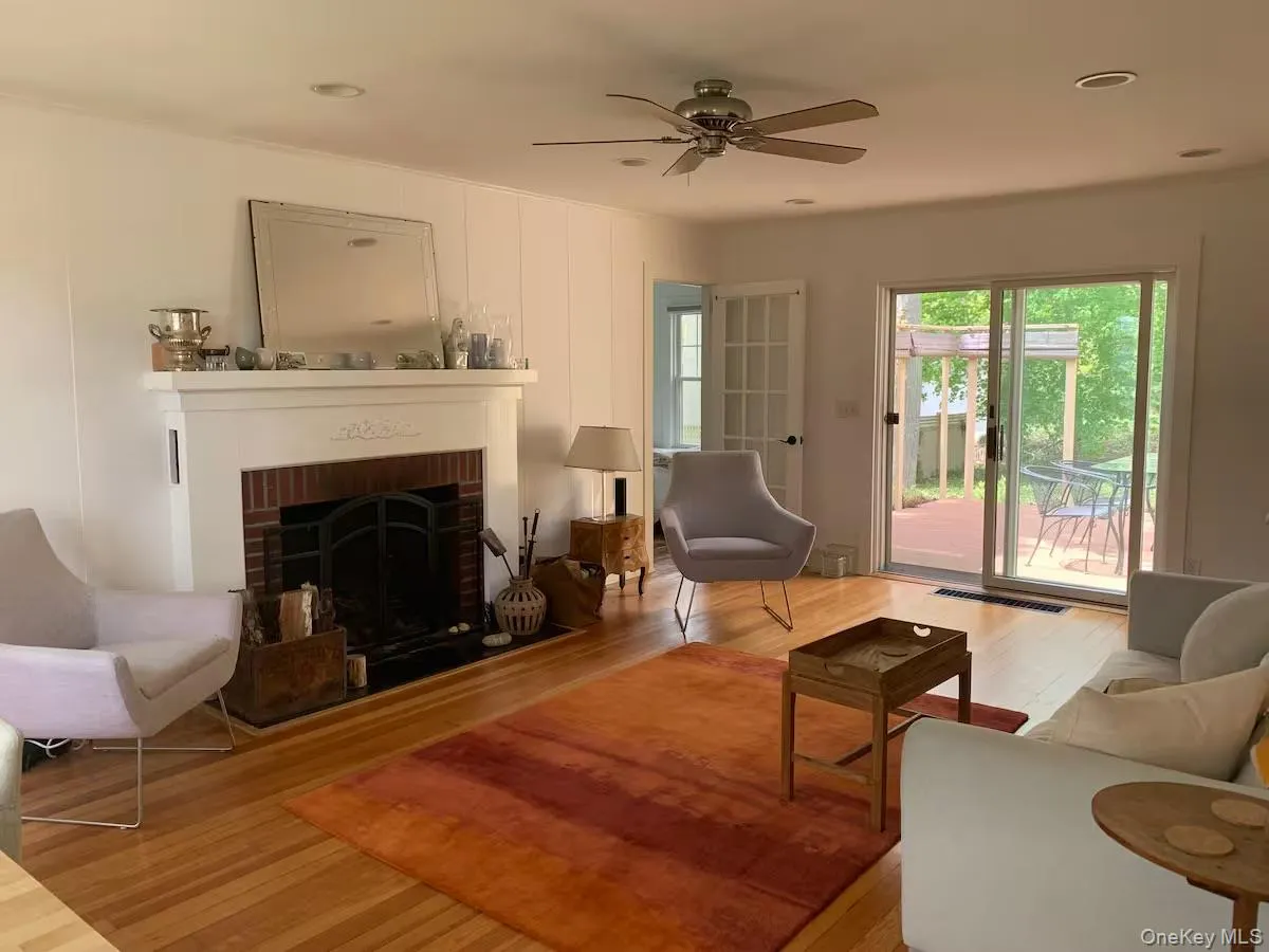 Living area with wood finished floors, a fireplace, and a ceiling fan Living area with wood finished floors, a fireplace, and a ceiling fan