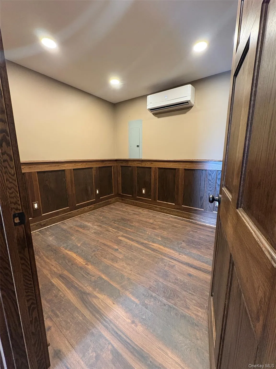 Empty room featuring a wainscoted wall, dark wood finished floors, recessed lighting, wooden walls, and electric panel Empty room featuring a wainscoted wall, dark wood finished floors, recessed lighting, wooden walls, and electric panel