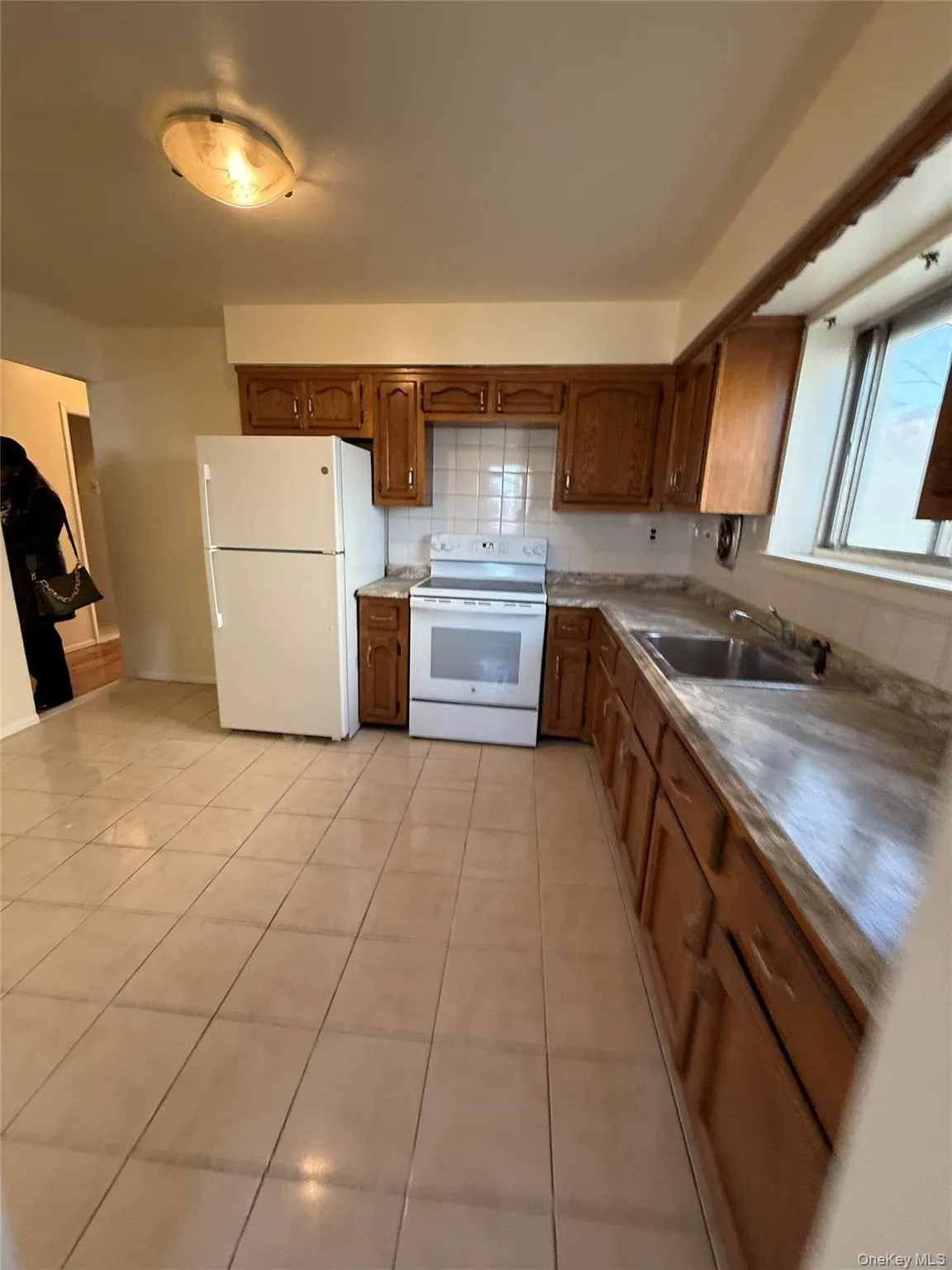 Kitchen featuring white appliances, brown cabinets, and light tile patterned flooring Kitchen featuring white appliances, brown cabinets, and light tile patterned flooring
