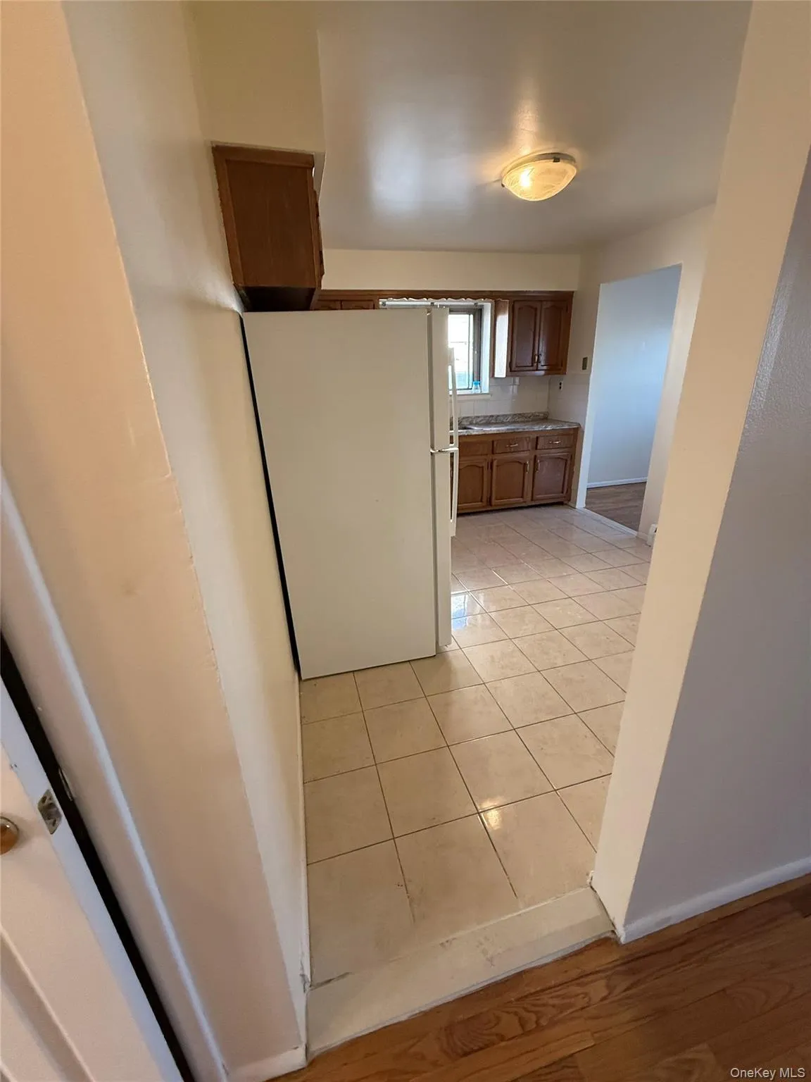 Kitchen with freestanding refrigerator, brown cabinets, light countertops, and light wood-type flooring Kitchen with freestanding refrigerator, brown cabinets, light countertops, and light wood-type flooring
