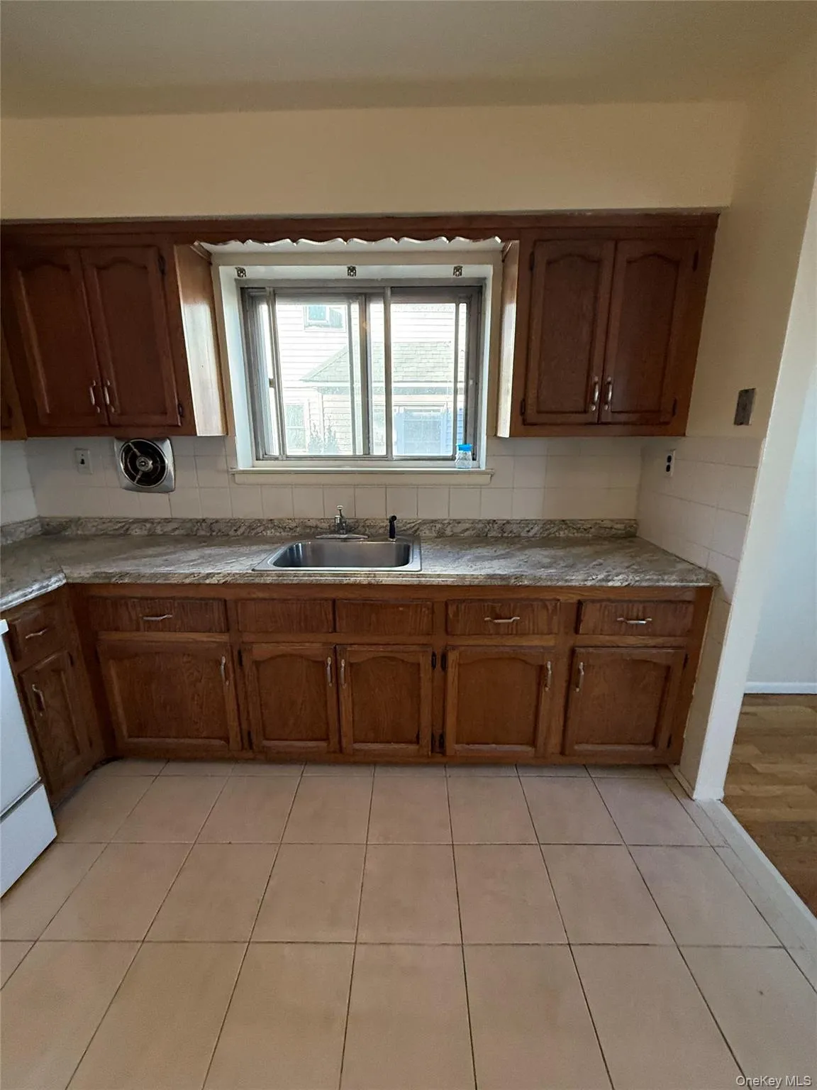 Kitchen featuring brown cabinets, light tile patterned floors, decorative backsplash, and white range Kitchen featuring brown cabinets, light tile patterned floors, decorative backsplash, and white range