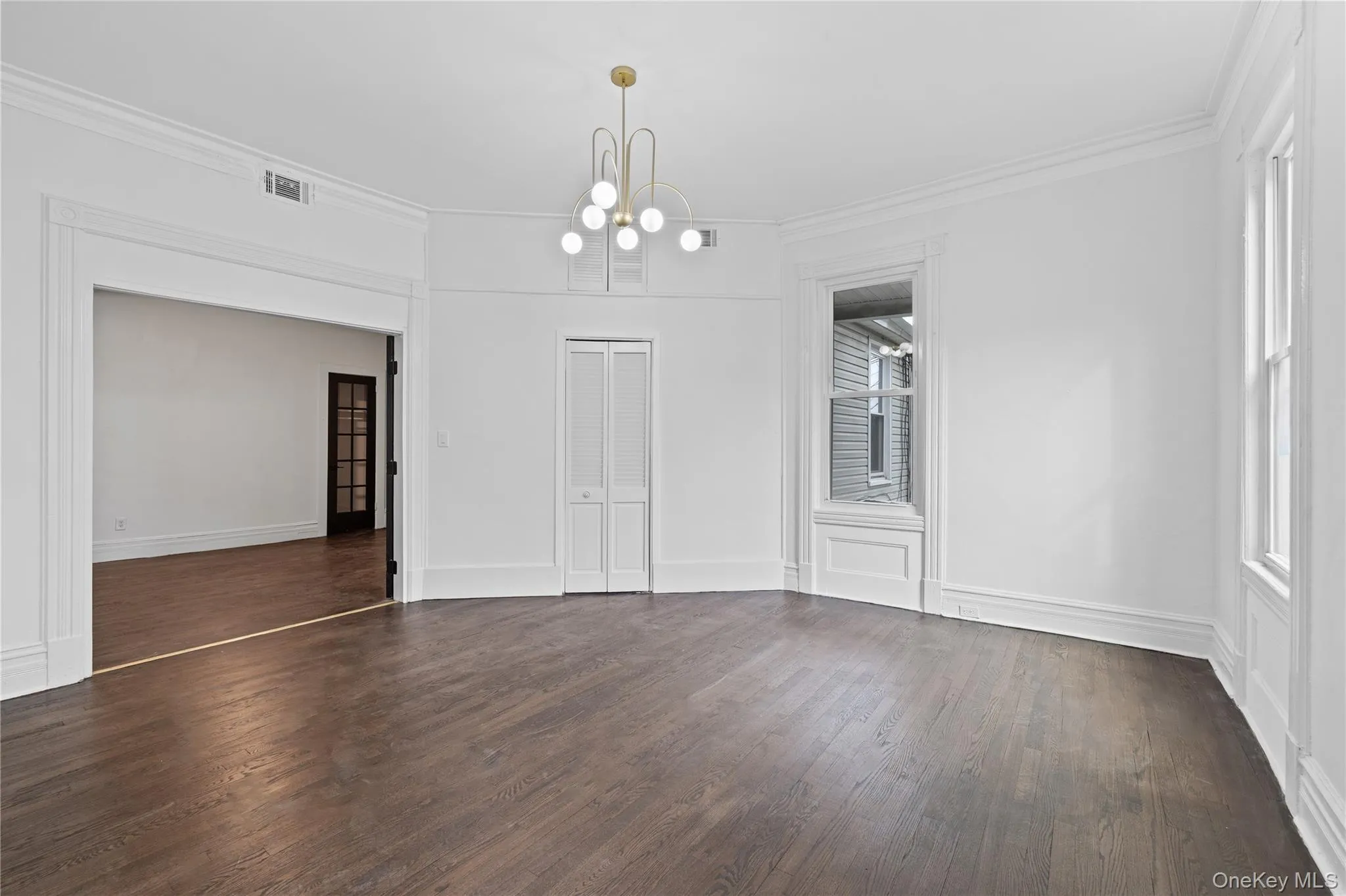 Unfurnished dining area featuring ornamental molding, an inviting chandelier, visible vents, and dark wood finished floors Unfurnished dining area featuring ornamental molding, an inviting chandelier, visible vents, and dark wood finished floors